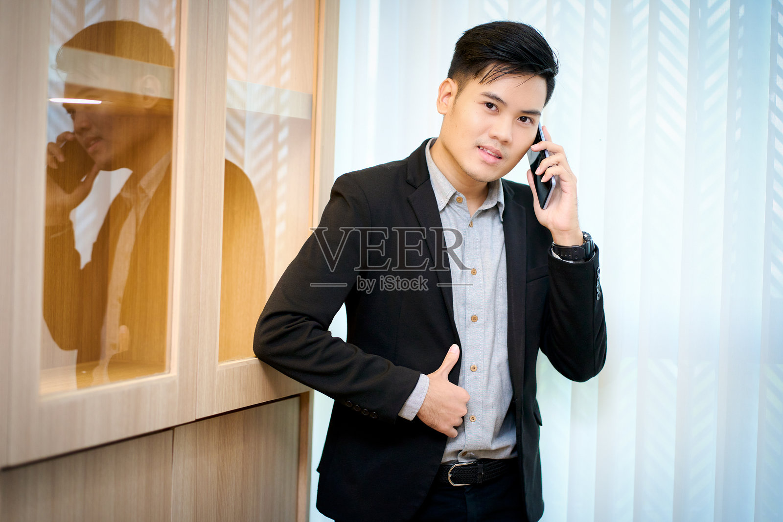 亚洲商人在办公室里站着用手机交谈照片摄影图片