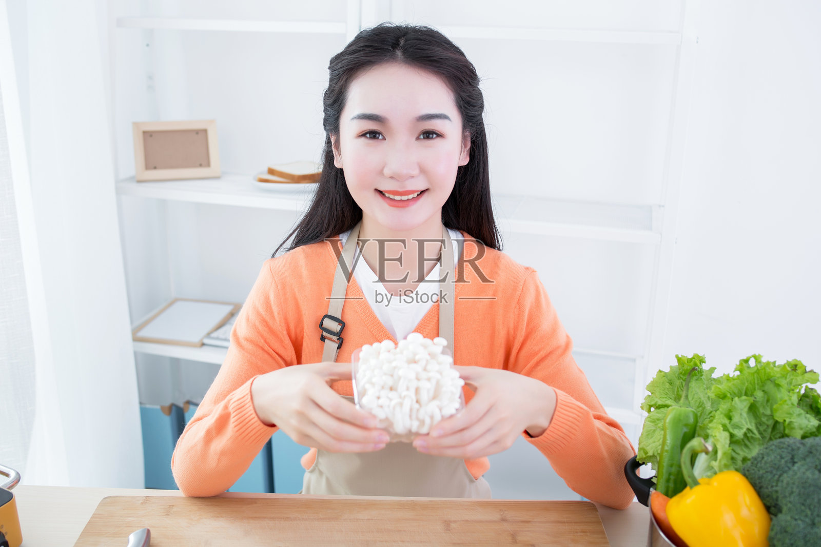 一位女性在明亮的厨房环境中端着食物照片摄影图片