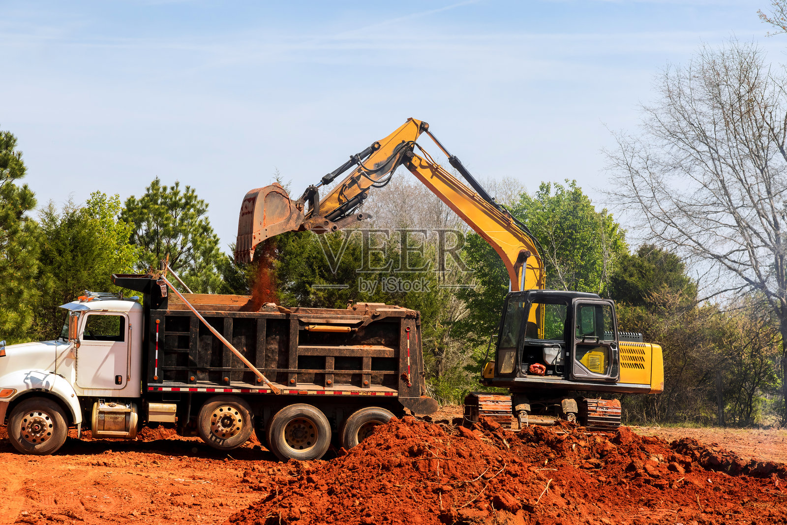 挖掘机在施工现场白天将土装入卡车中照片摄影图片