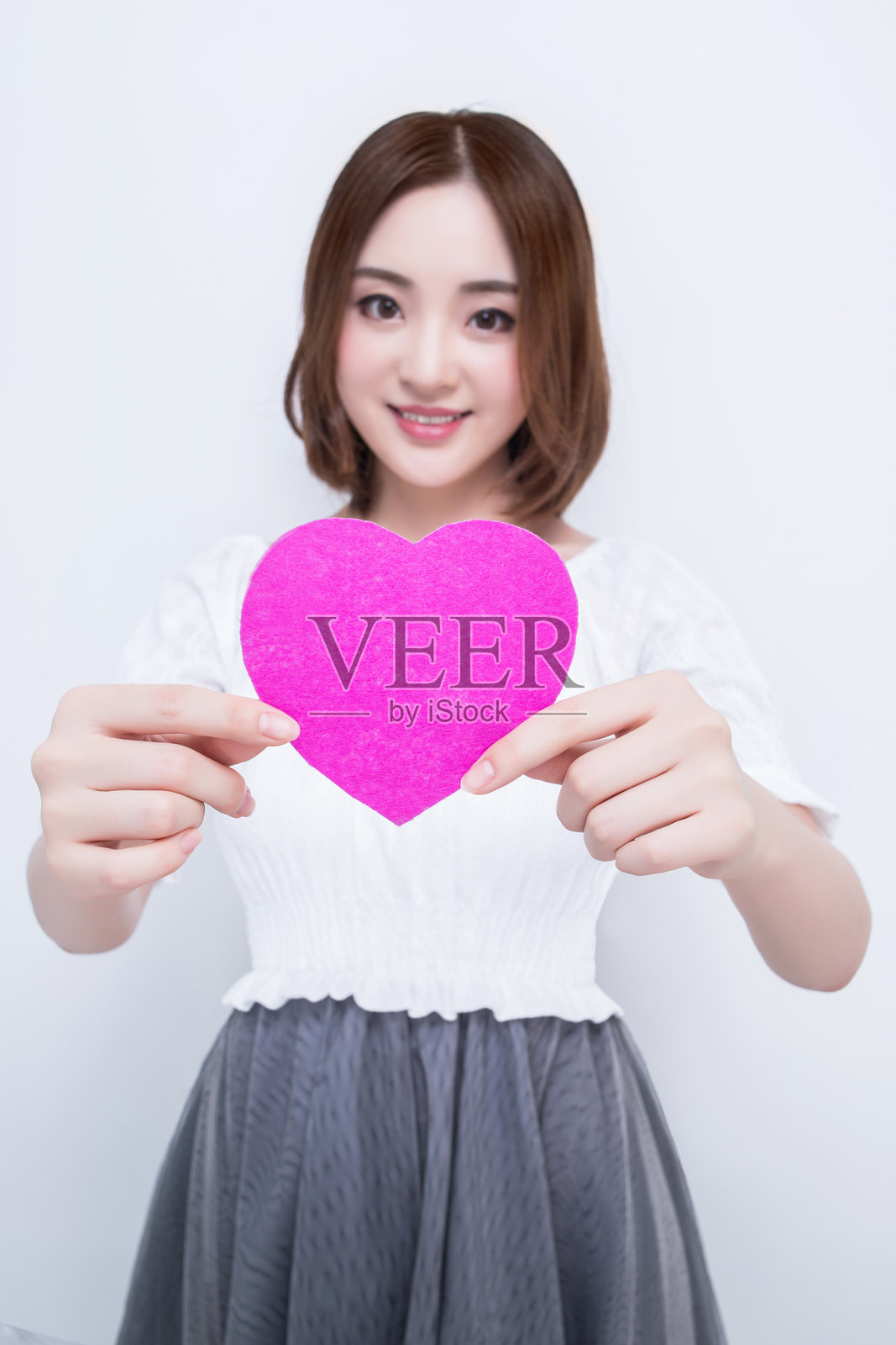 年轻女性手持粉色心形物品照片摄影图片