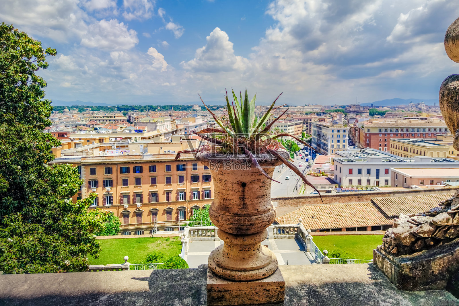 一只经典的石制花瓶,上面种着多肉植物,位于梵蒂冈的阳台上,俯瞰罗马的全景城市风光和历史屋顶。照片摄影图片