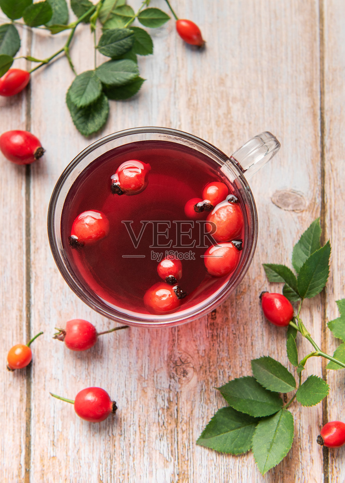 在乡村风格的木桌上,玻璃杯中泡着玫瑰果茶照片摄影图片