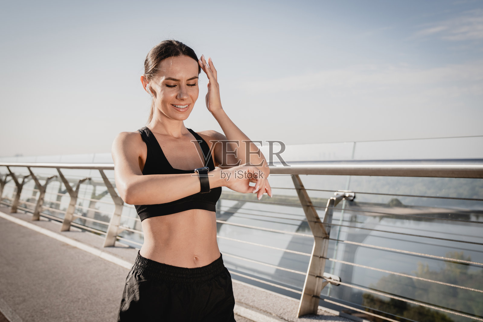 穿着运动服的健康女性在晨跑后查看智能手表,监测心率和卡路里消耗。户外运动与现代科技,留白空间。照片摄影图片