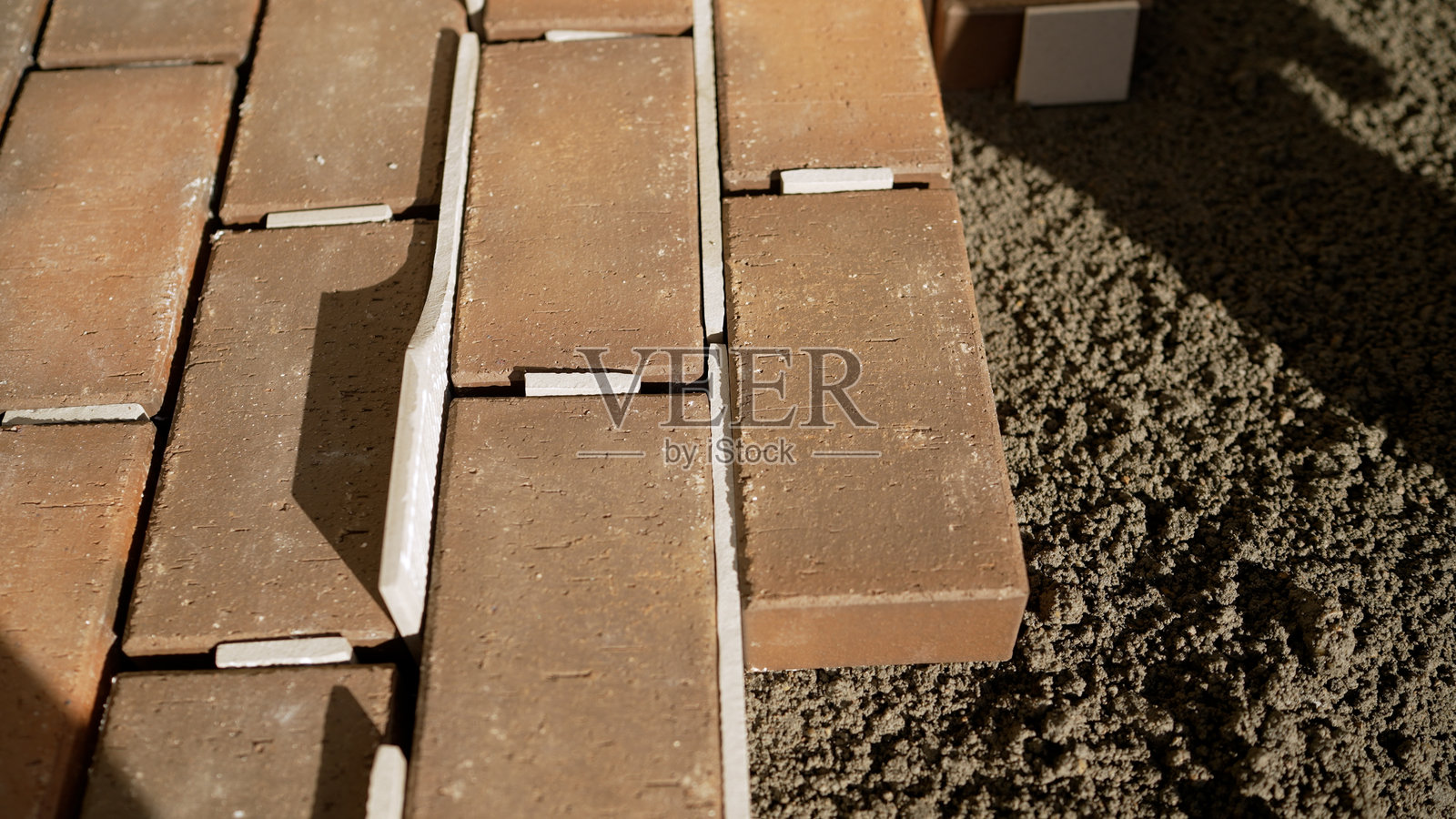 建筑工人在铺设粘土砖铺路石,正在打造一个露台照片摄影图片