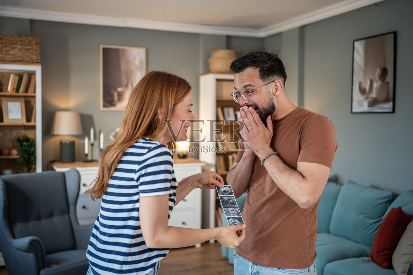 幸福的情侣在家中查看他们宝宝的超声波扫描图。照片摄影图片