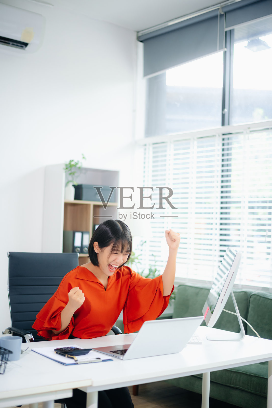 快乐的亚洲女性在明亮的办公室里庆祝成功的信息。照片摄影图片