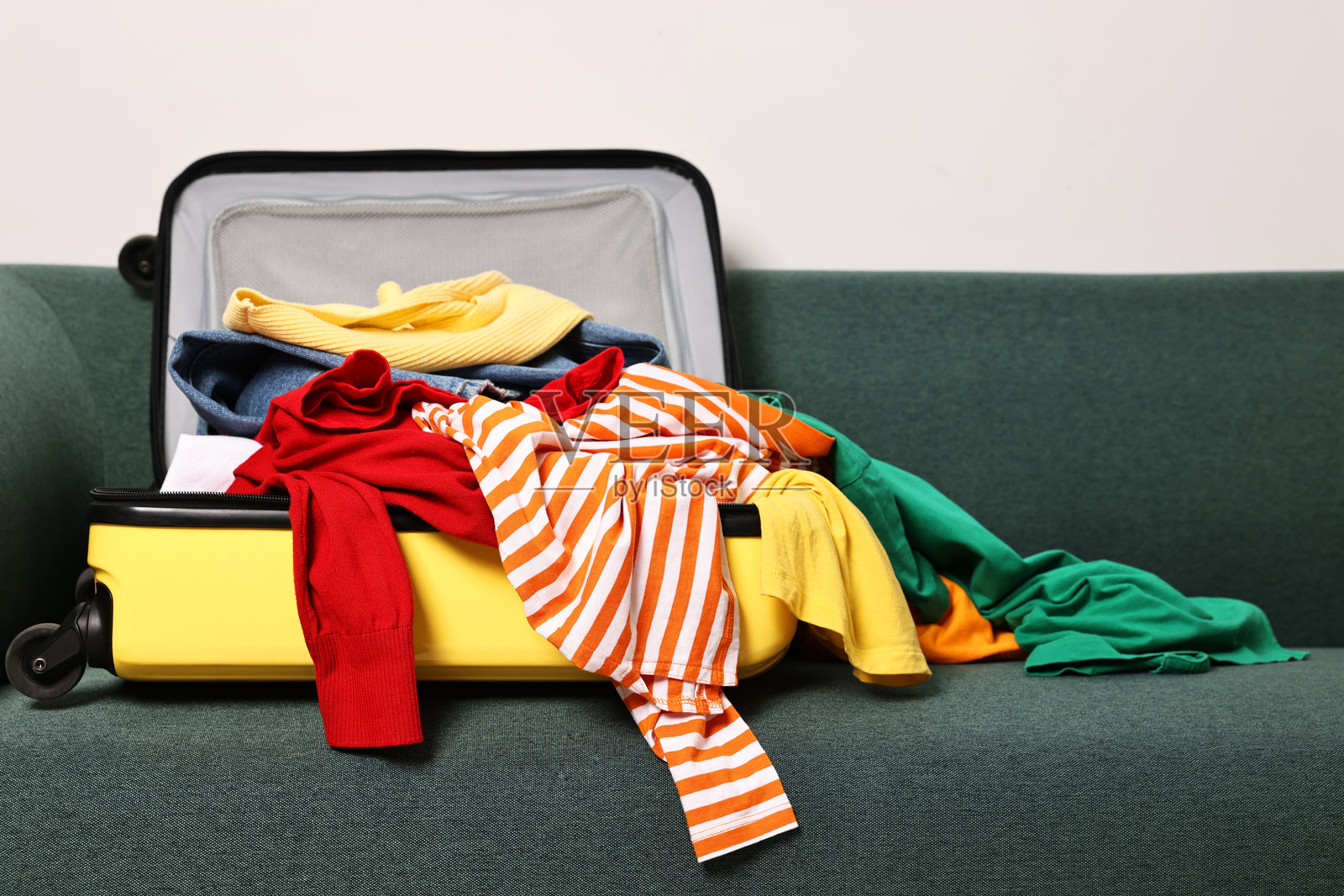 沙发上放着一个装满各种凌乱衣物的打开行李箱照片摄影图片