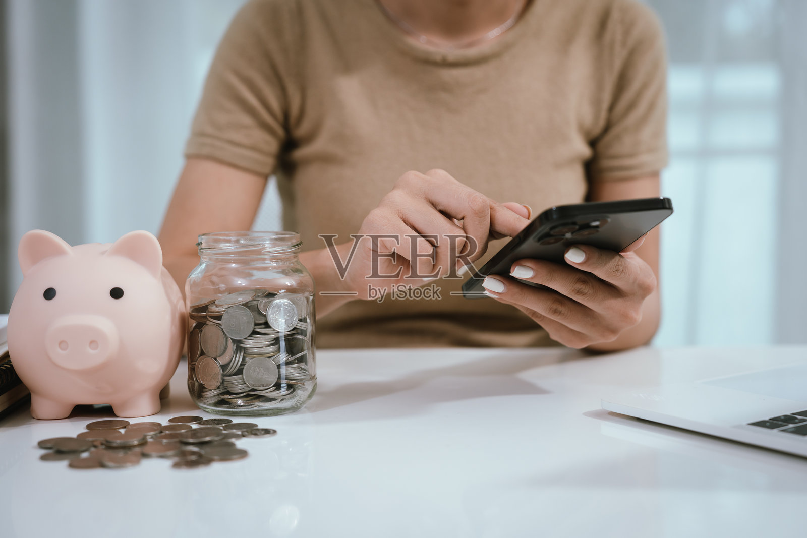 一位亚洲女性计划将她的钱分成硬币和储蓄罐,象征着预算、财务规划、储蓄和聪明的理财管理。照片摄影图片