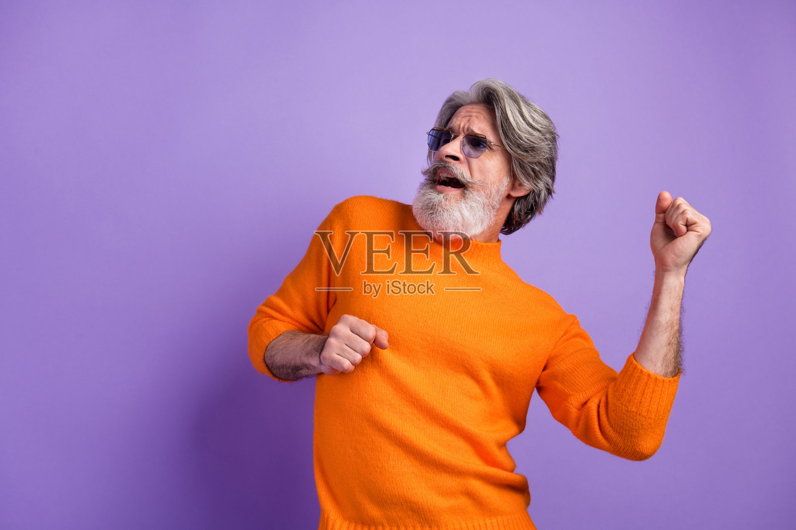 快乐的老年男子在紫色背景下享受音乐舞蹈,面带微笑。照片摄影图片