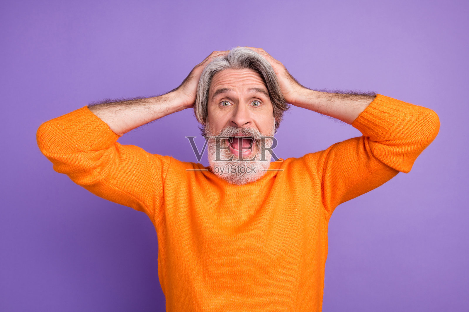 成熟男性惊讶地用手捂住头,因失败、错误和麻烦而感到担忧,背景为紫色。照片摄影图片
