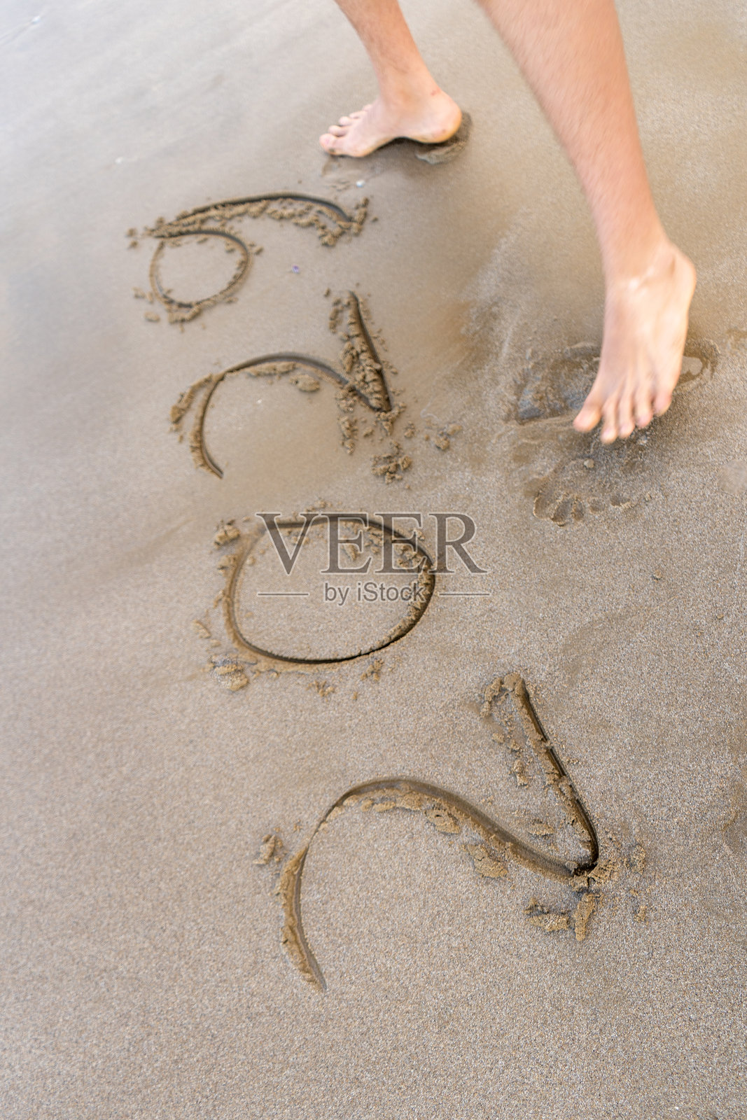 沙滩上写着2029的数字。脚的俯视图照片摄影图片