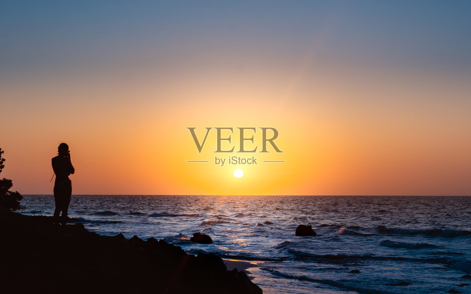 海滩上的日落,女人的剪影。照片摄影图片