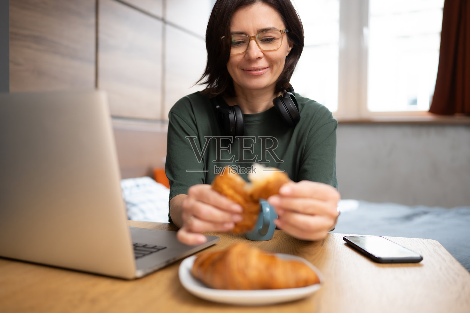 漂亮的女人享用可颂作为早餐照片摄影图片