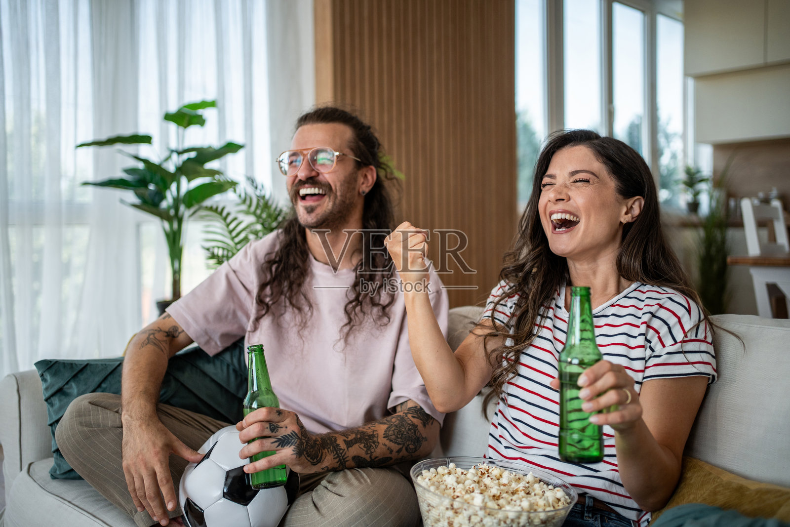 一对情侣在看电视足球比赛时欢呼和大笑照片摄影图片