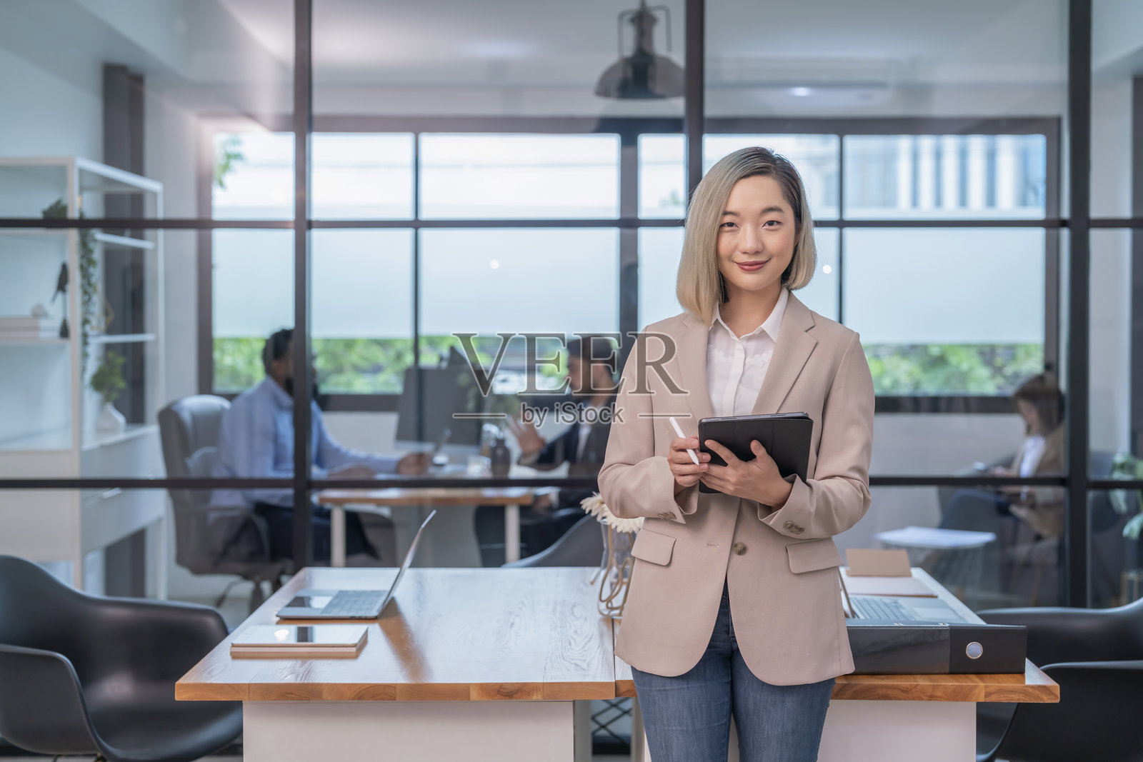 亚洲女性公司员工在工作场所的桌子上使用平板电脑工作,商务员工在办公室工作照片摄影图片