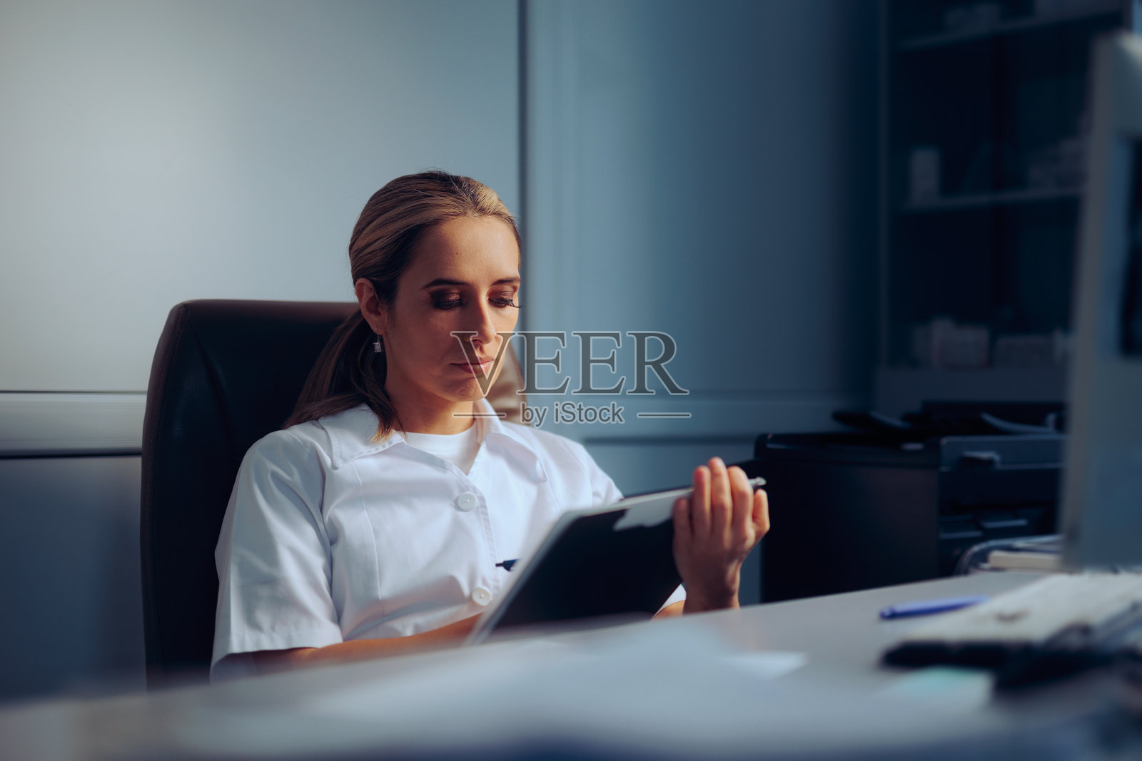 医生在办公室里查看剪贴板上的医疗报告照片摄影图片