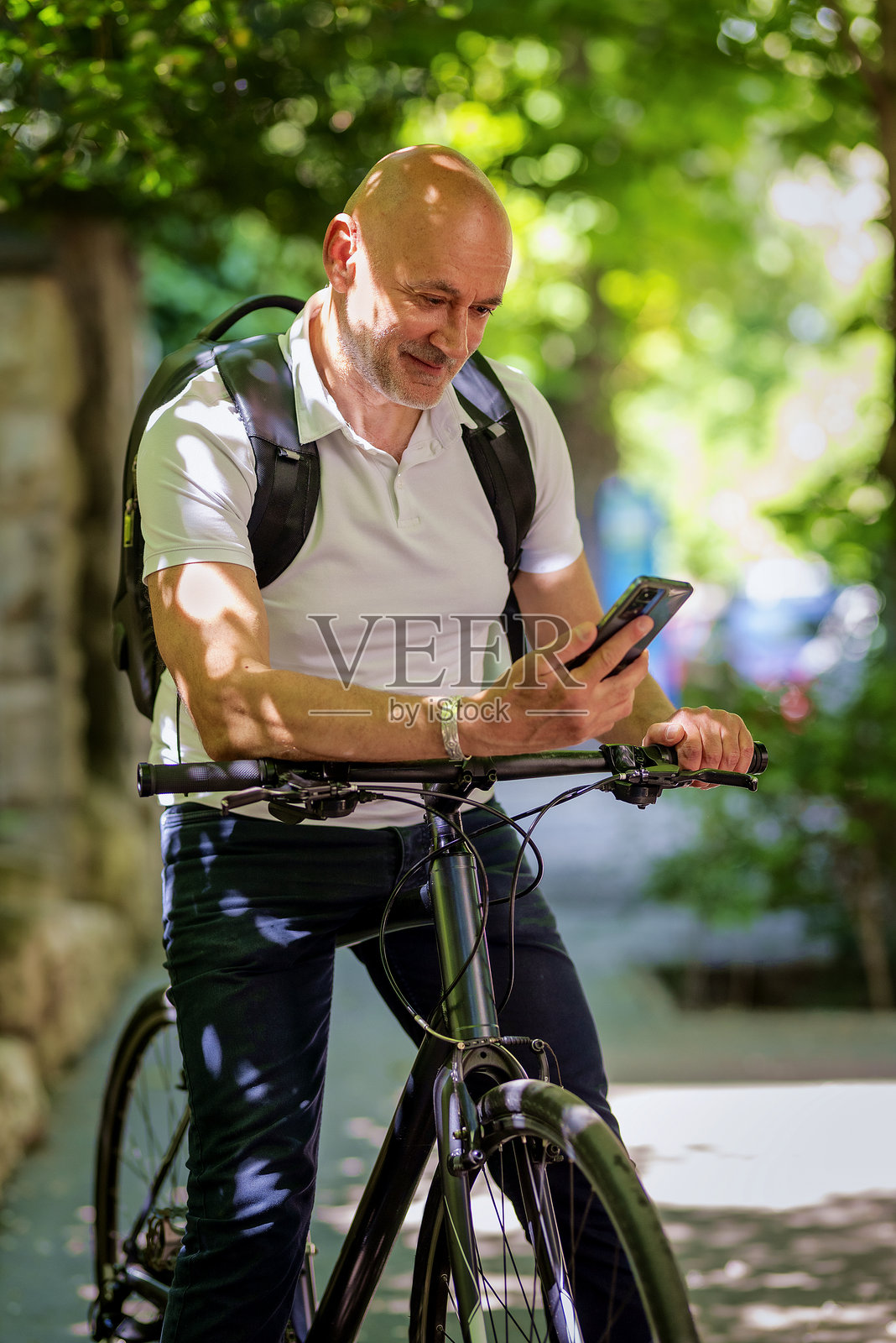 城市中骑自行车的老年人正在使用手机照片摄影图片