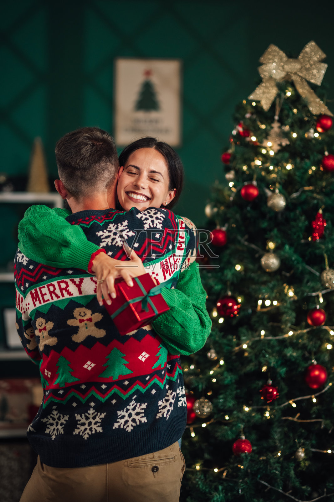 年轻女性抱着圣诞礼物,拥抱她的男朋友照片摄影图片