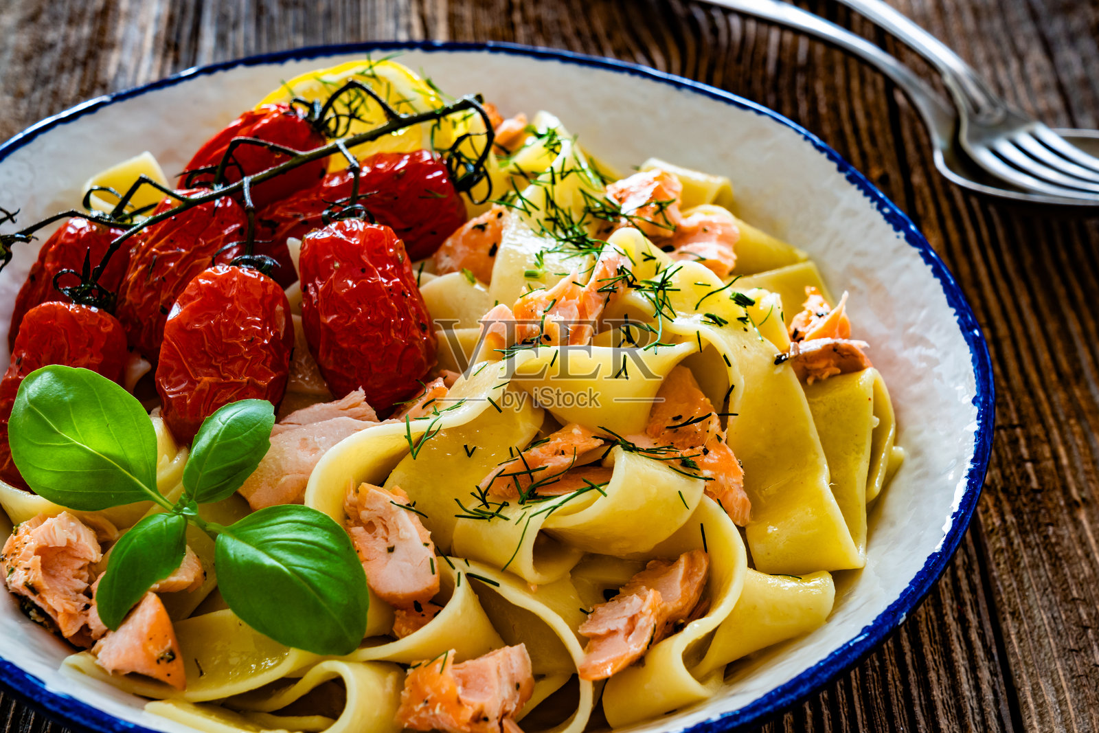 木桌上的烤三文鱼樱桃番茄意大利面照片摄影图片