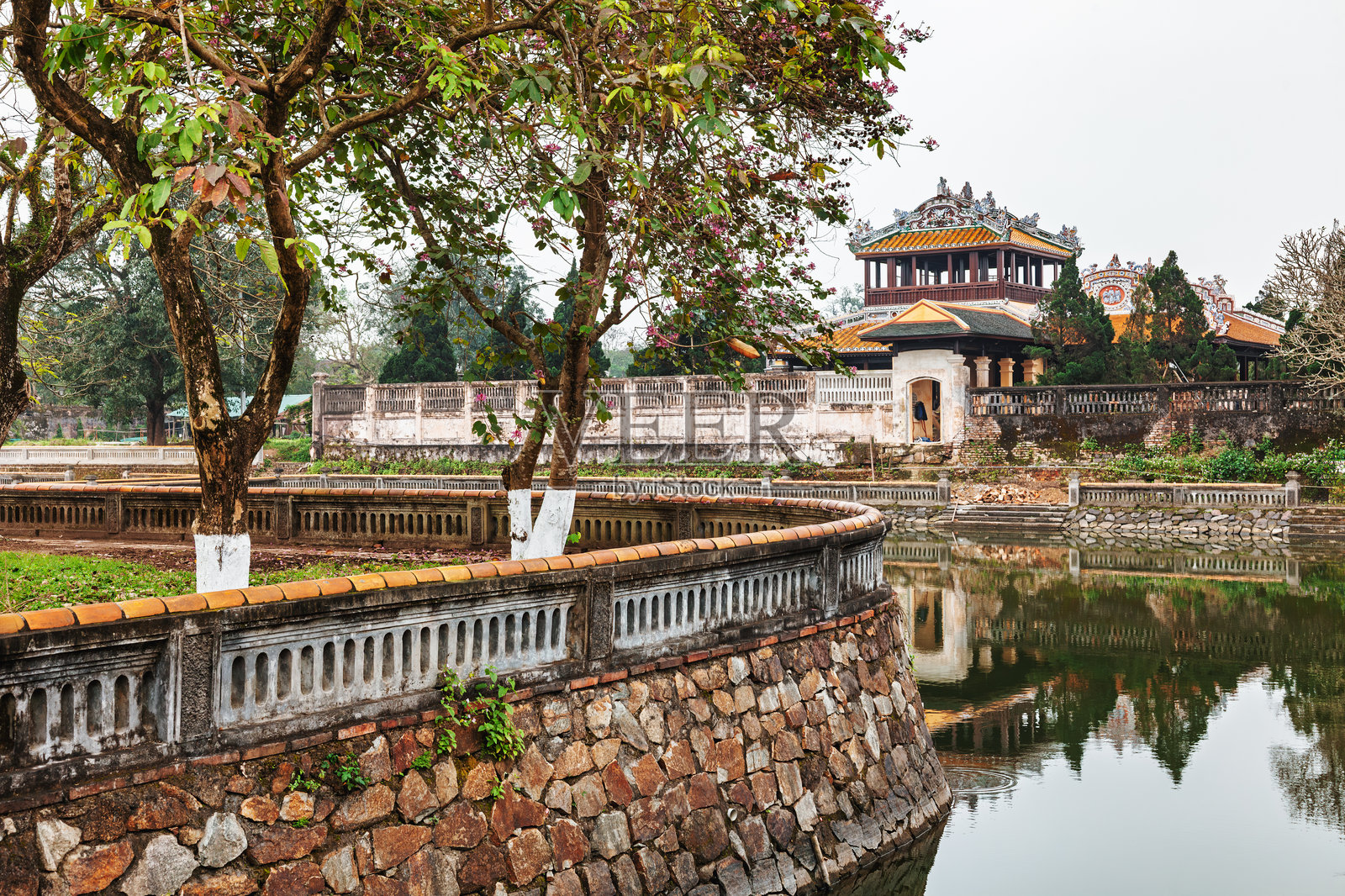越南历史悠久的宫殿,映照在环绕着石头和树木的护城河中,位于顺化皇城。照片摄影图片