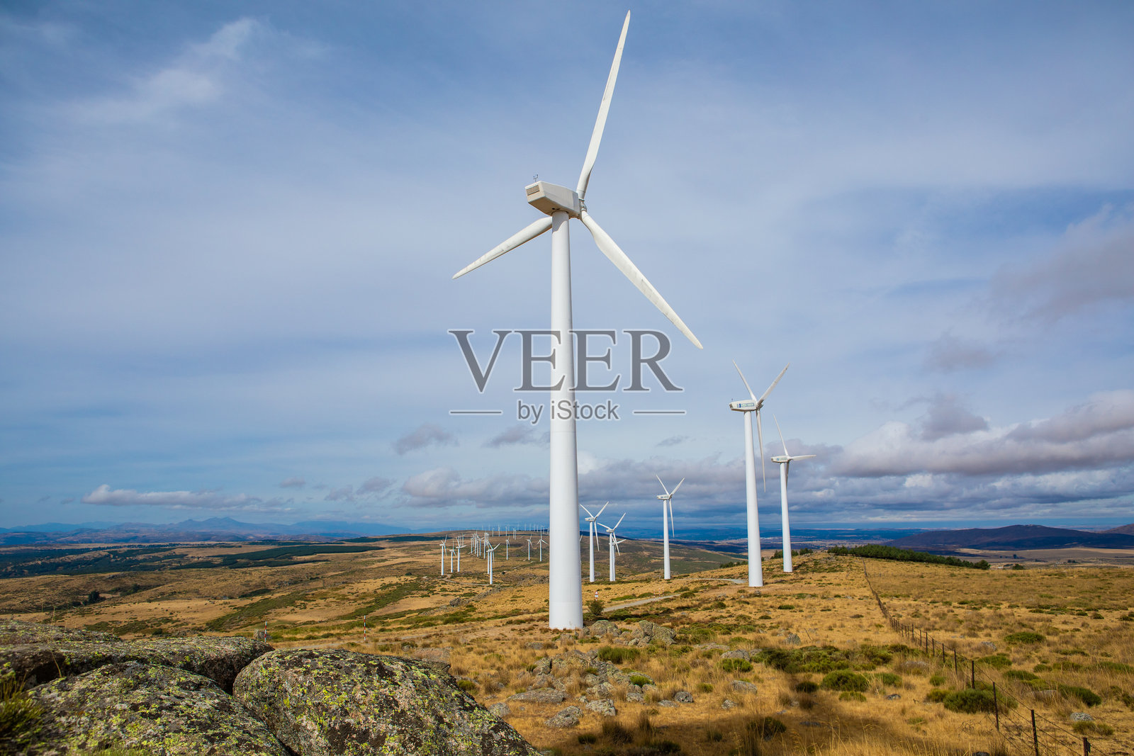 风力涡轮机在风景如画的清澈天空和起伏的山丘中产生清洁能源照片摄影图片