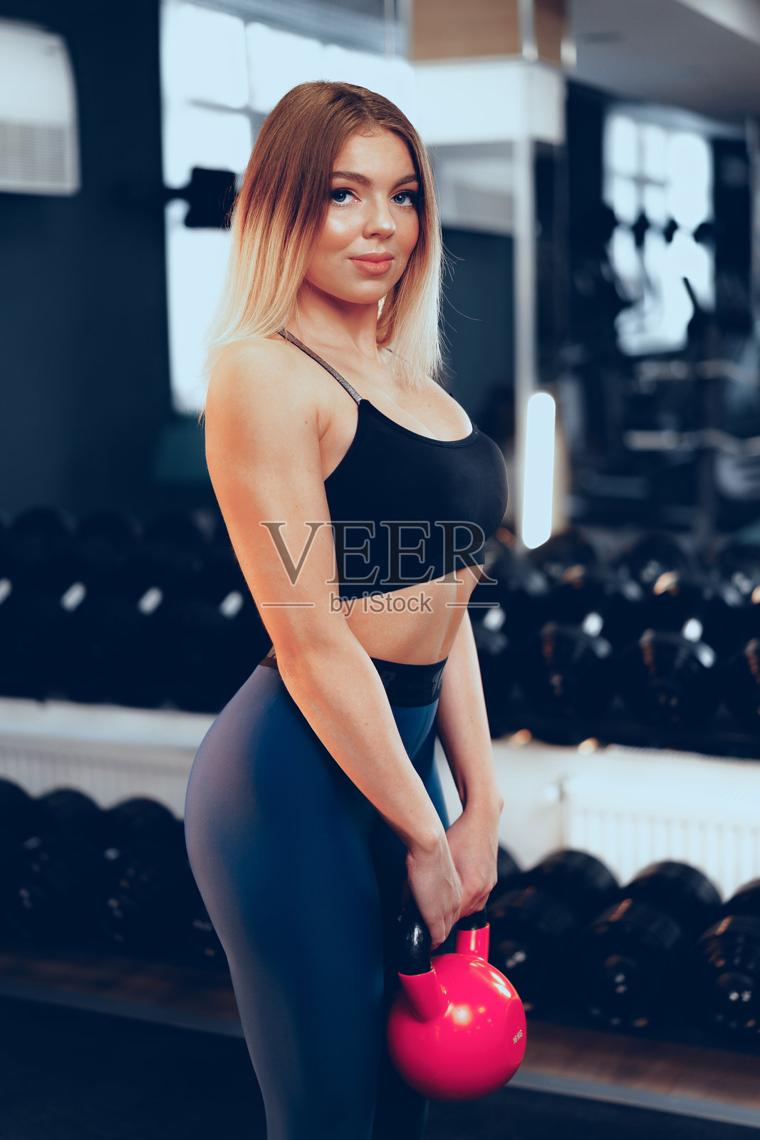 身材曲线优美的年轻金发女性在健身房举哑铃照片摄影图片