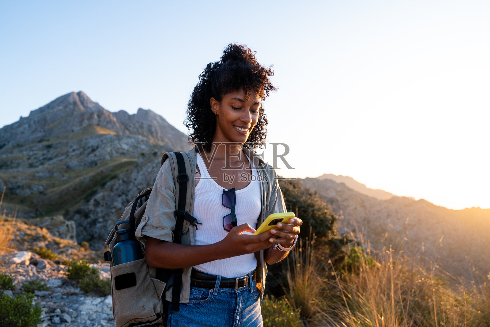 年轻女性在马约卡的特拉蒙塔纳山脉徒步旅行时使用智能手机照片摄影图片