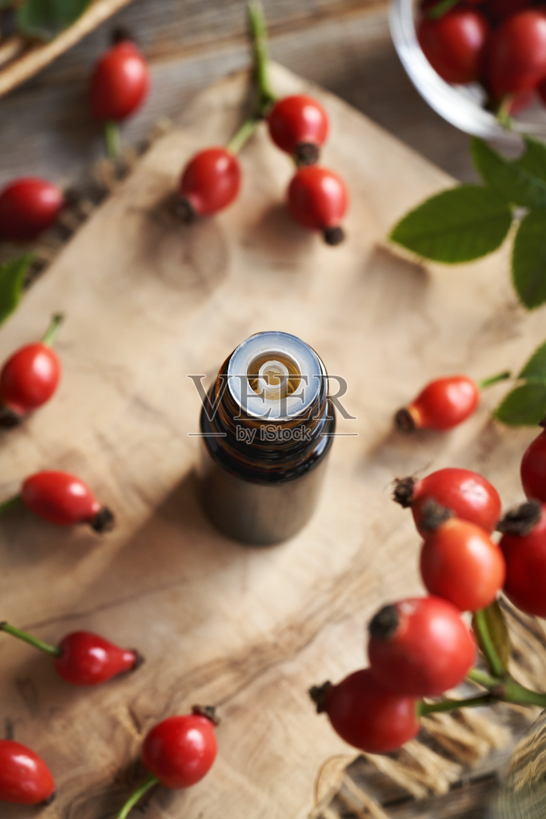 棕色瓶中的玫瑰果种子油与新鲜玫瑰果照片摄影图片