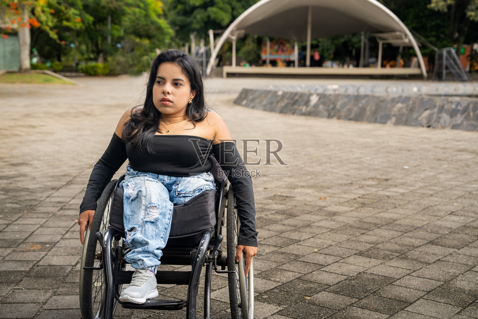 年轻的残疾女性在城市街道上坐在轮椅里照片摄影图片