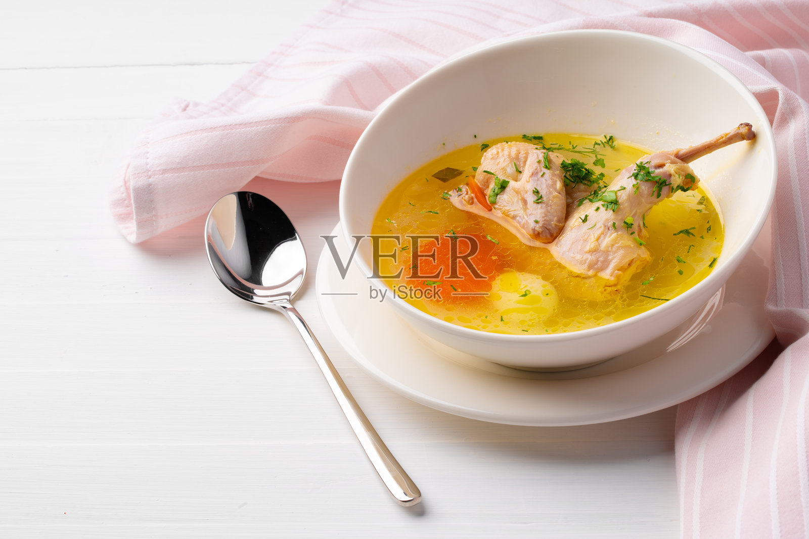 白色碗中的鸡肉蔬菜汤,放在木桌上照片摄影图片