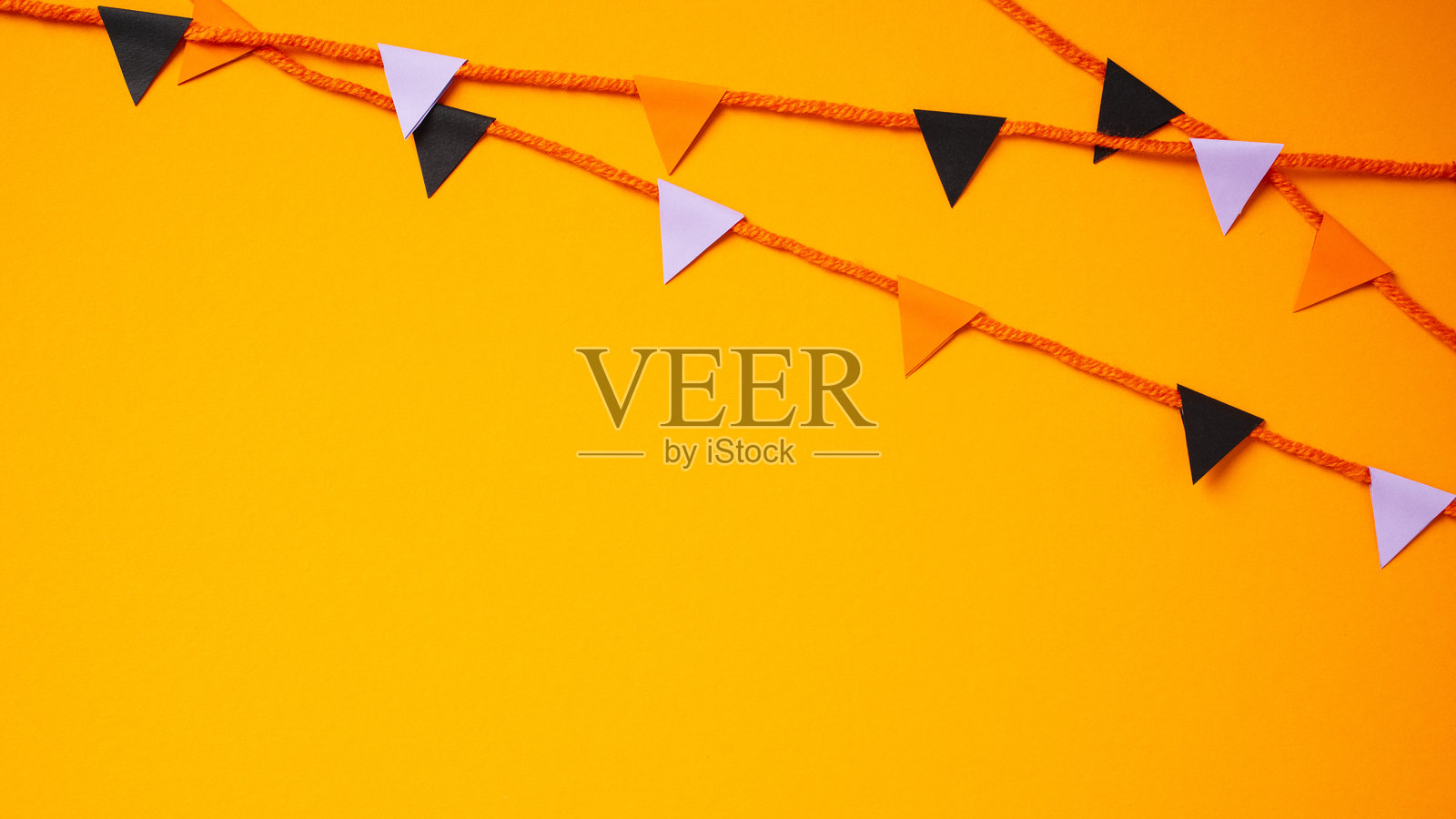 万圣节庆祝活动的横幅,橙色背景上装饰着彩旗串。照片摄影图片