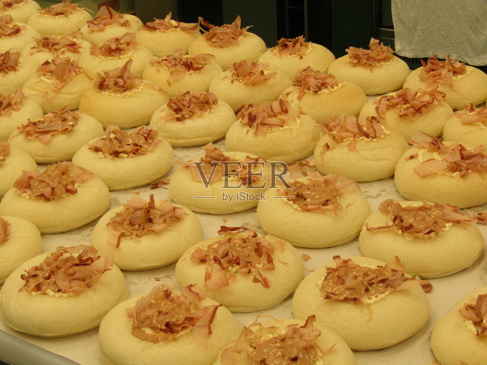 在日本当地面包店烘焙的美味白面包,上面撒有酱汁和鲣鱼 flakes,这是一种独特的日本美食。照片摄影图片