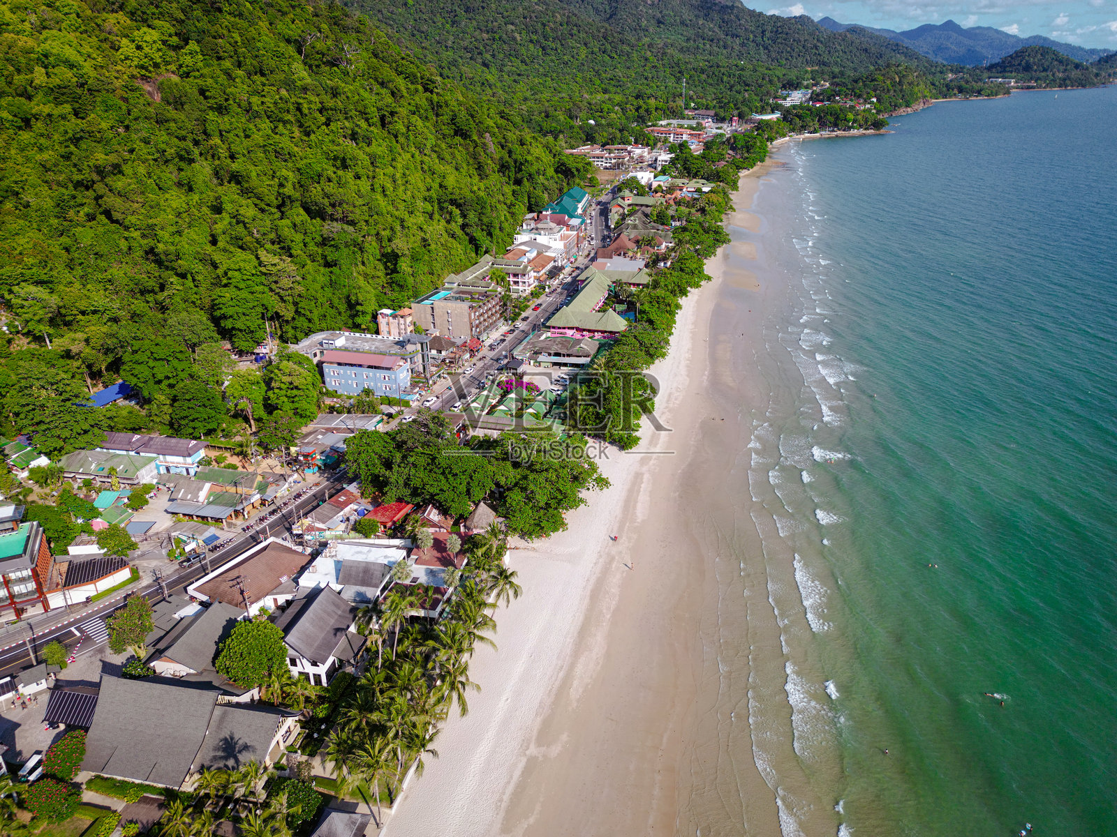 热带白沙海滩的鸟瞰图,美丽的度假酒店位于海滨,椰子树环绕。照片摄影图片