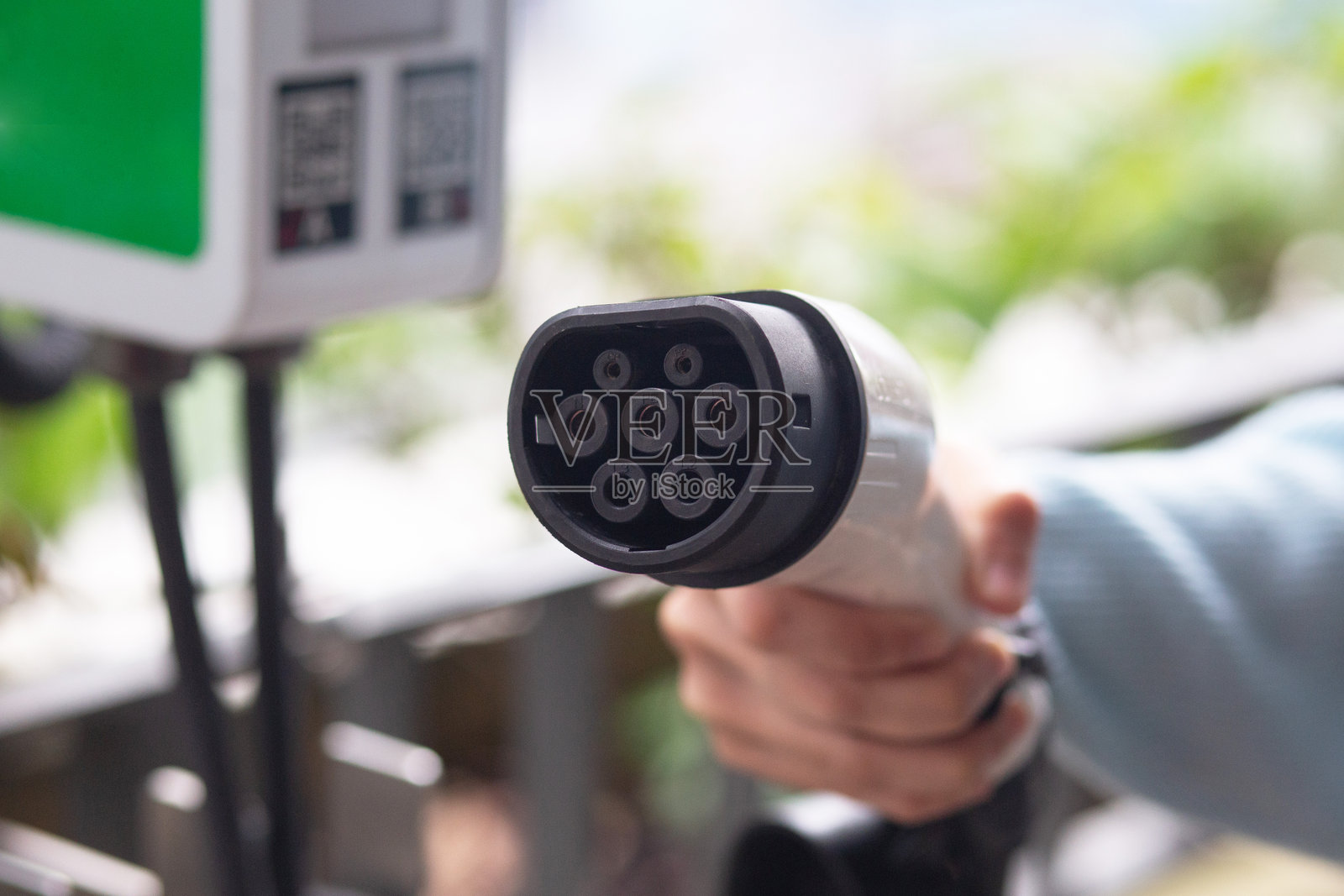 准备充电:手持电动车充电器的女性照片摄影图片