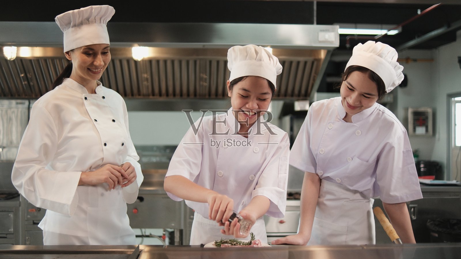 实习生在餐厅厨房与大厨一起练习烹饪。照片摄影图片