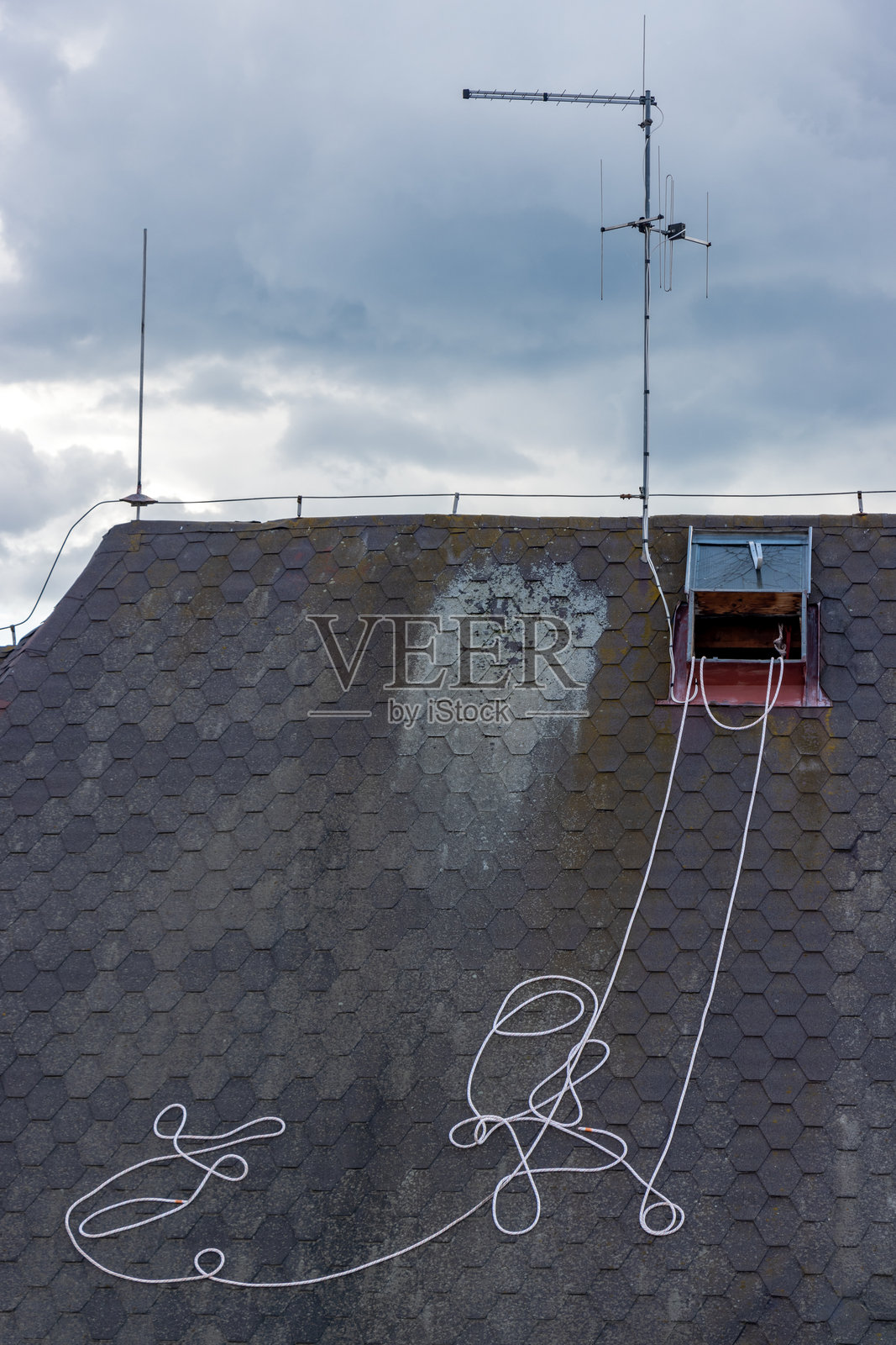 从天窗拉出的绳子躺在屋顶上,旁边有天线。照片摄影图片