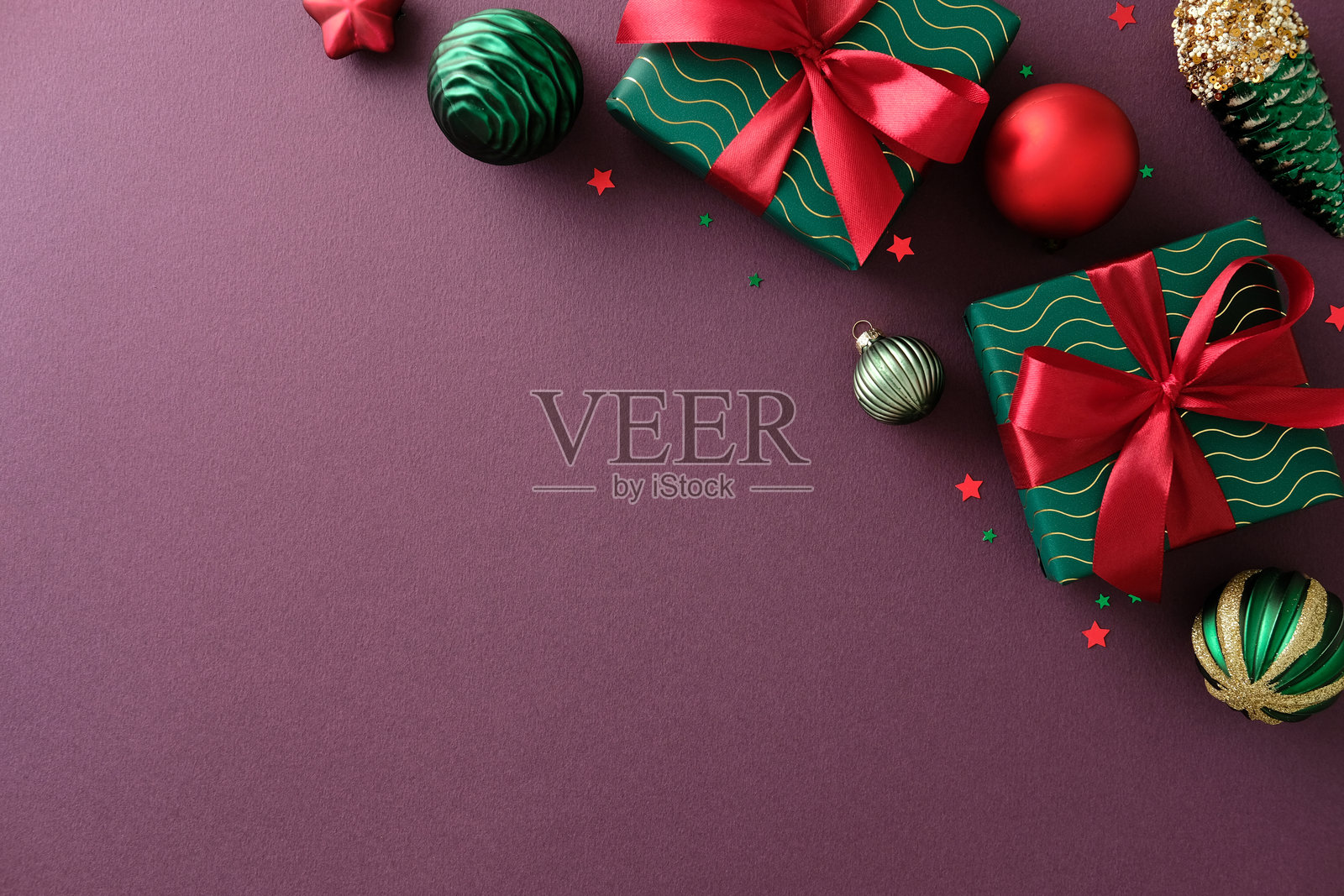 深红色背景上的圣诞布局,角落里有彩球、松果和包好的礼物。平铺视角,顶部视图,留白空间。照片摄影图片