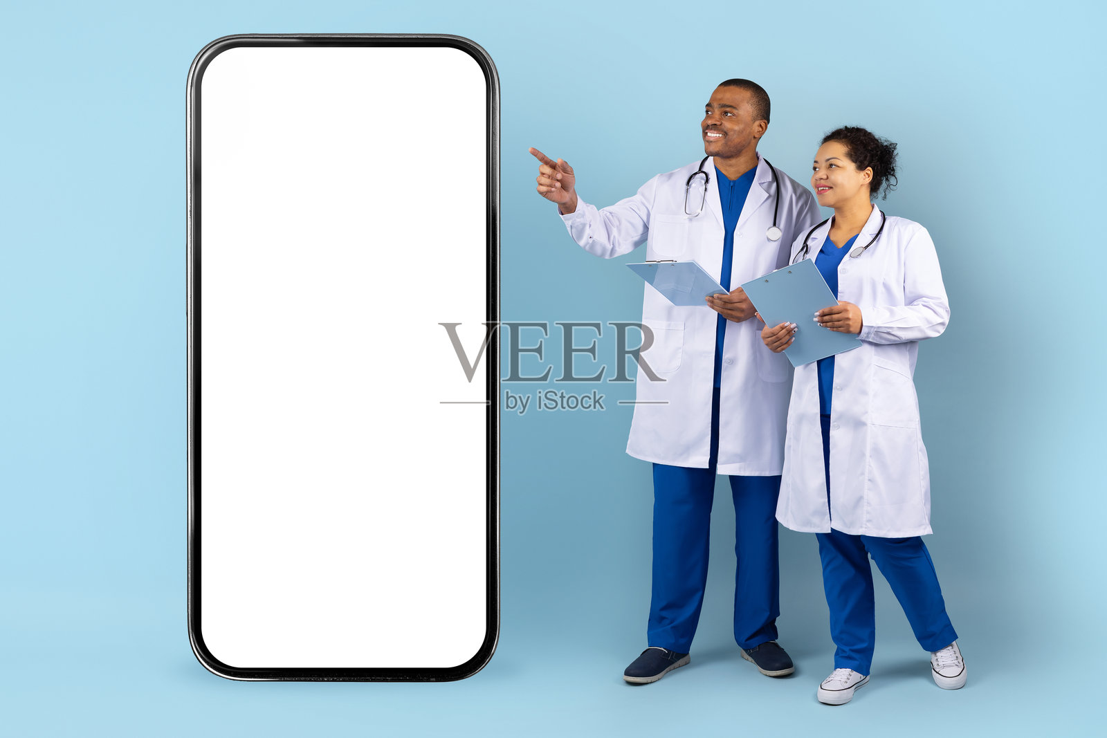 两位非裔美国医生站在工作室的大型空白智能手机屏幕旁边照片摄影图片