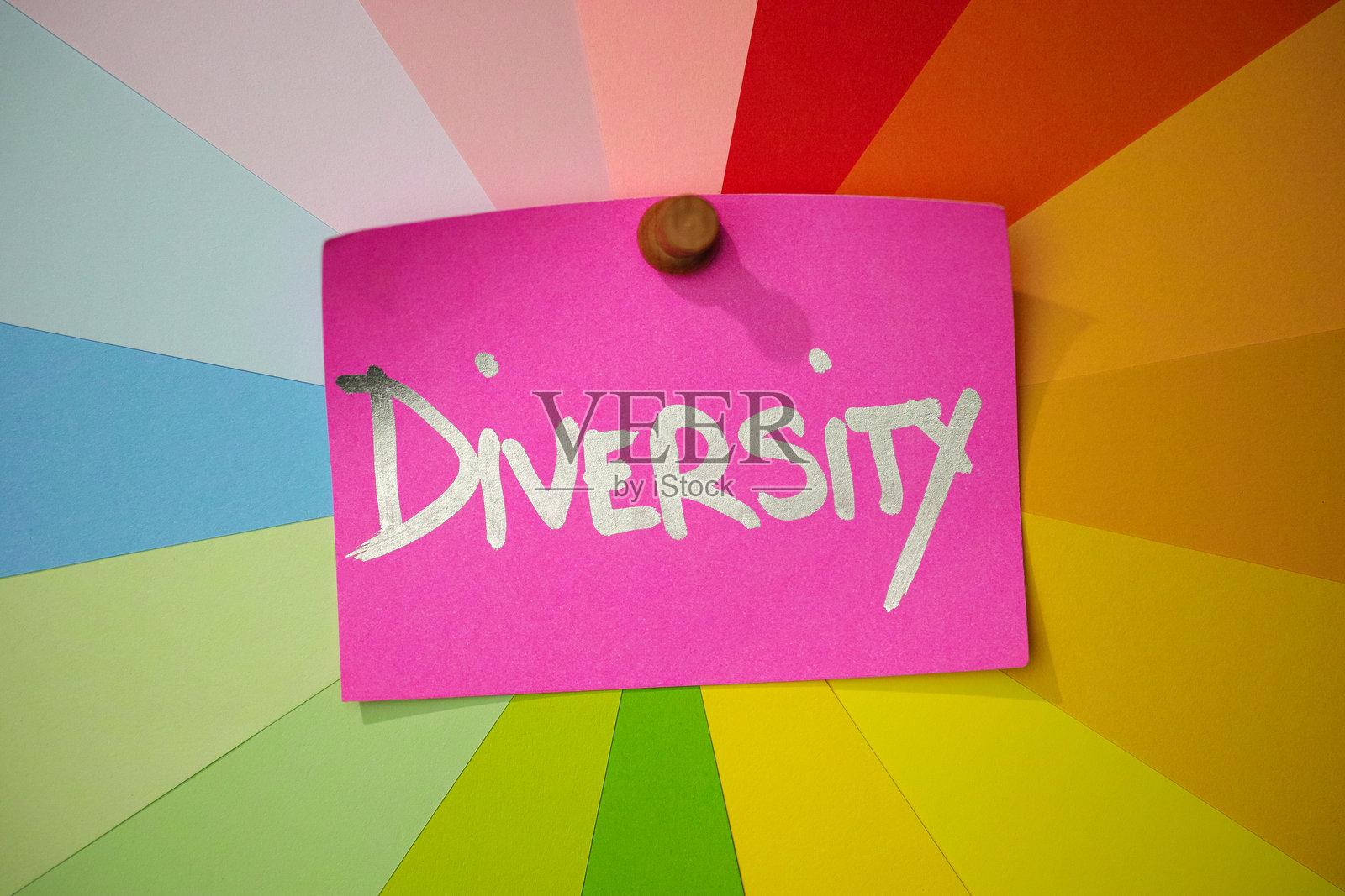 粉色纸条别在五彩缤纷的不同粉彩彩虹色纸条上,上面写着单词“多样性”。照片摄影图片