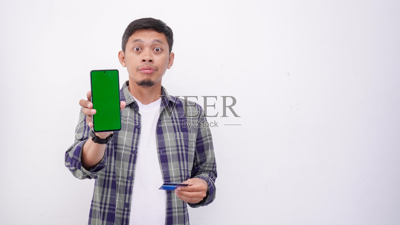 亚洲男子手持带绿屏的智能手机和信用卡照片摄影图片