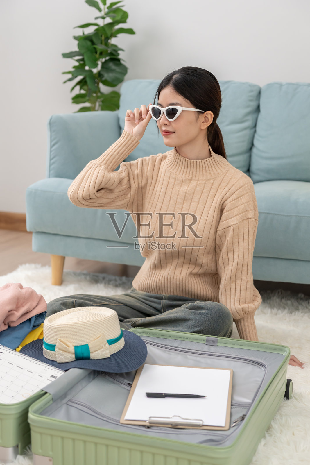 女性旅行者正在准备和试戴旅行用的太阳镜。她们正在整理衣物和个人物品。在旅行前打包行李。假期、度假时间、长周末、夏季。照片摄影图片