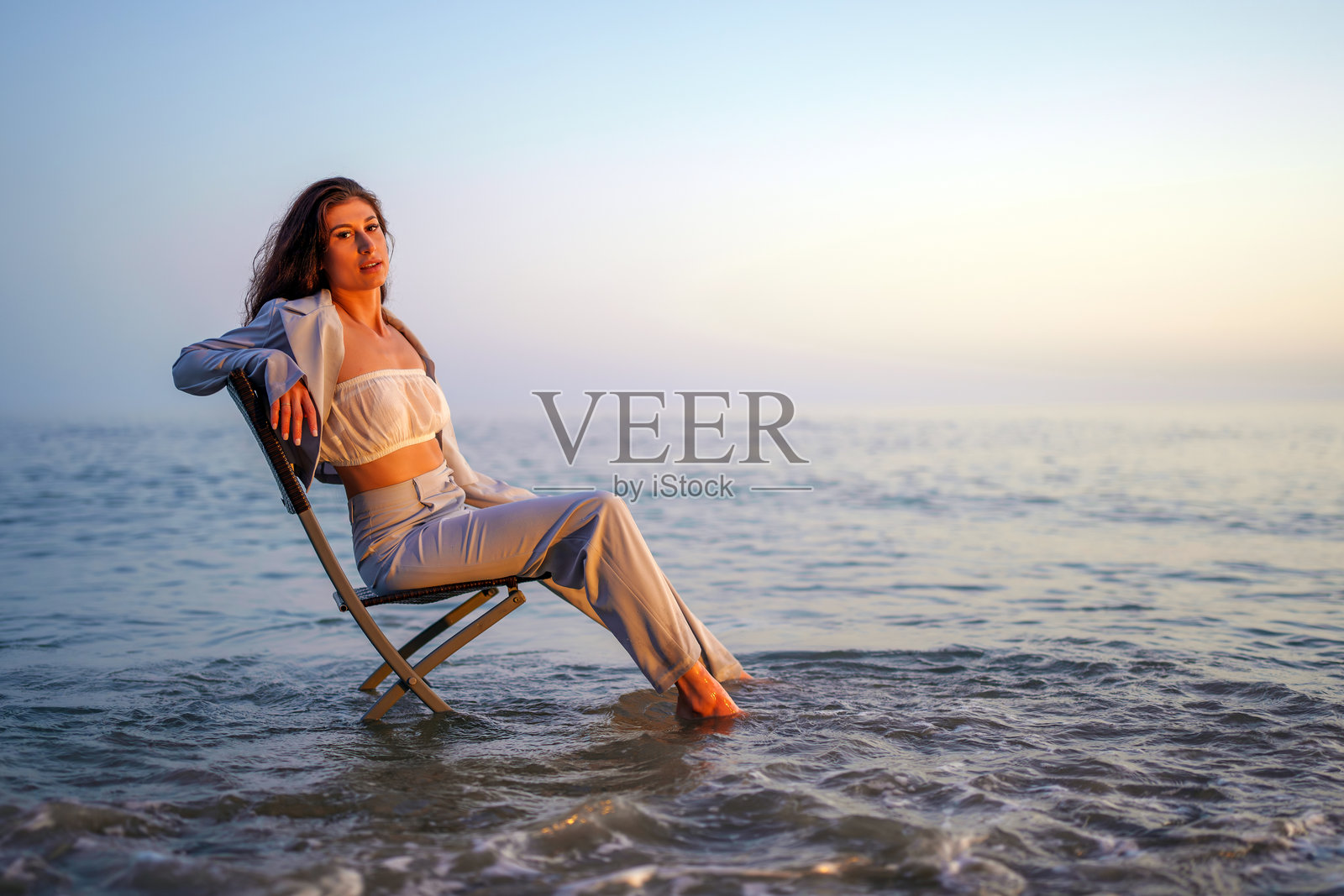 女商人在海边的椅子上享受日落时光照片摄影图片