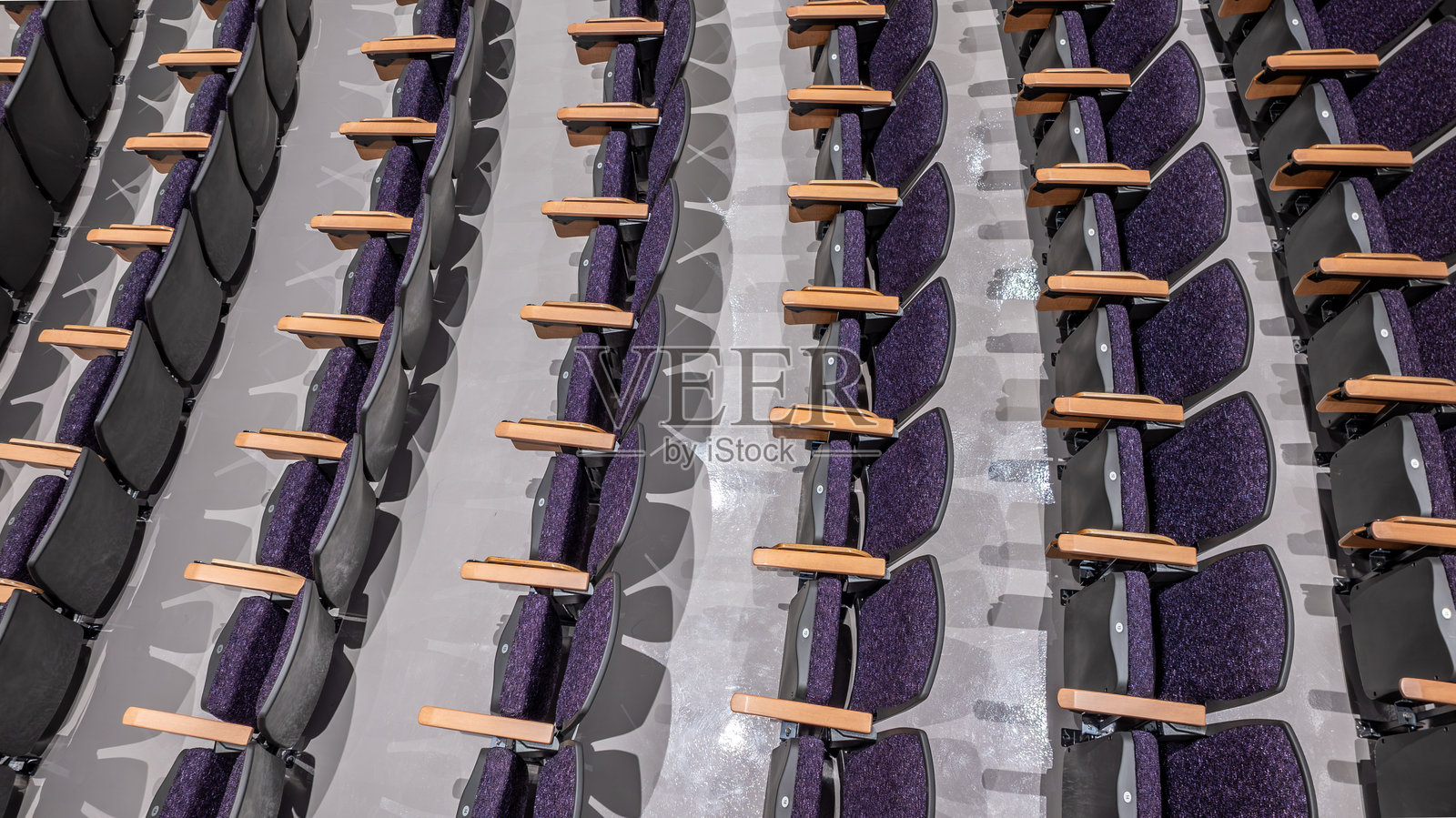紫色软垫礼堂座椅,灰色混凝土地板的椅子,在一个空旷的集会、教室、剧院空间,从无人机视角俯视。照片摄影图片