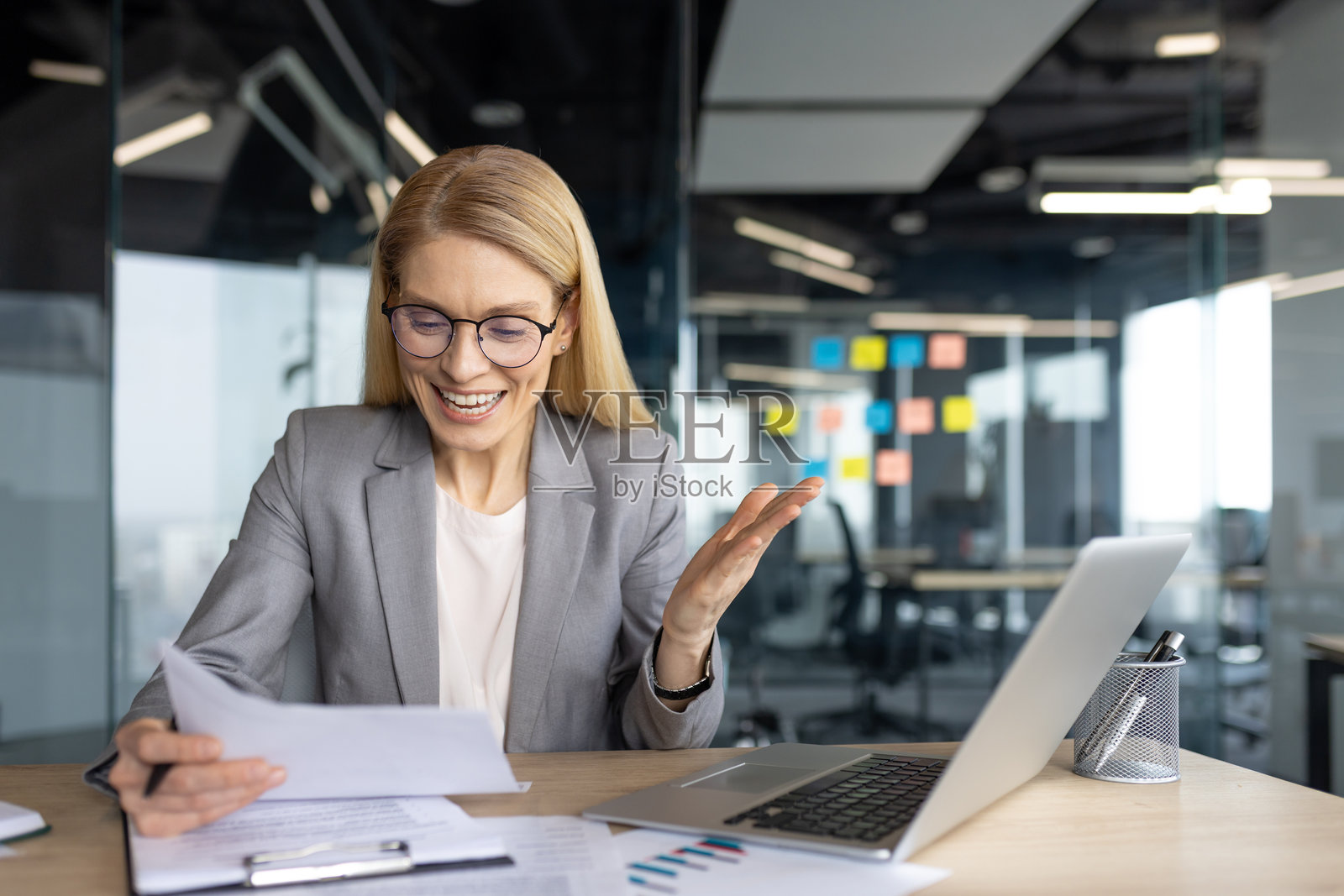 快乐的女商人在办公室处理文件和笔记本电脑。照片摄影图片