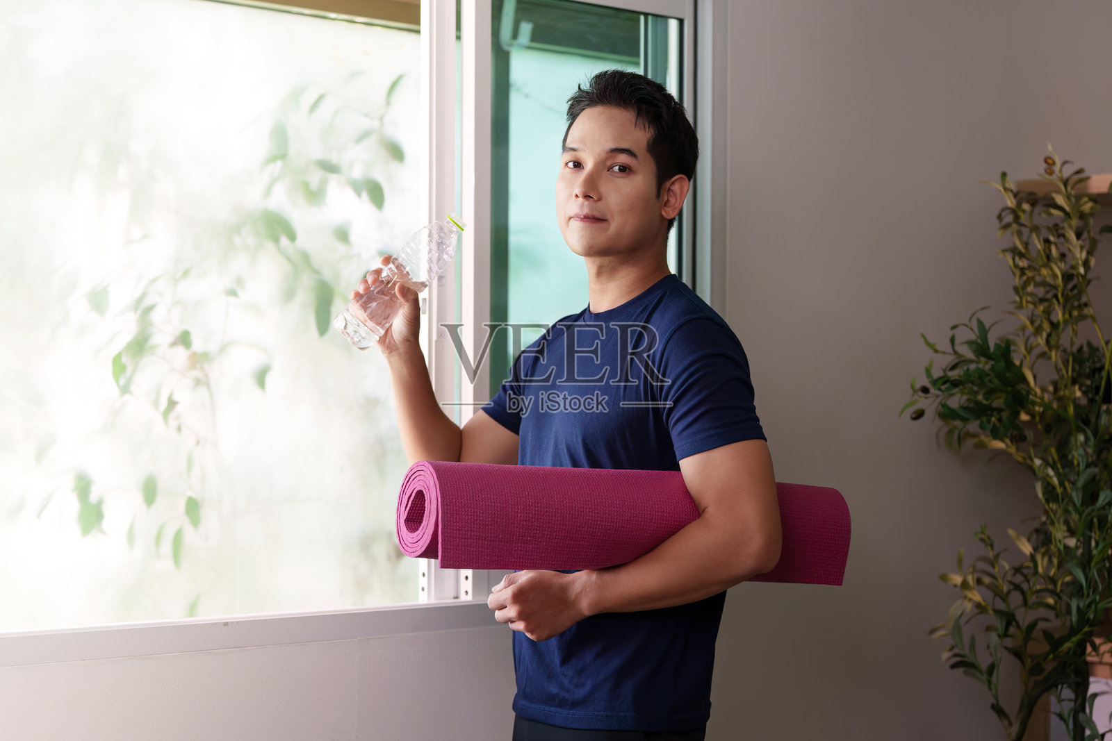 水分补充与健身。个人手持水瓶和瑜伽垫。照片摄影图片