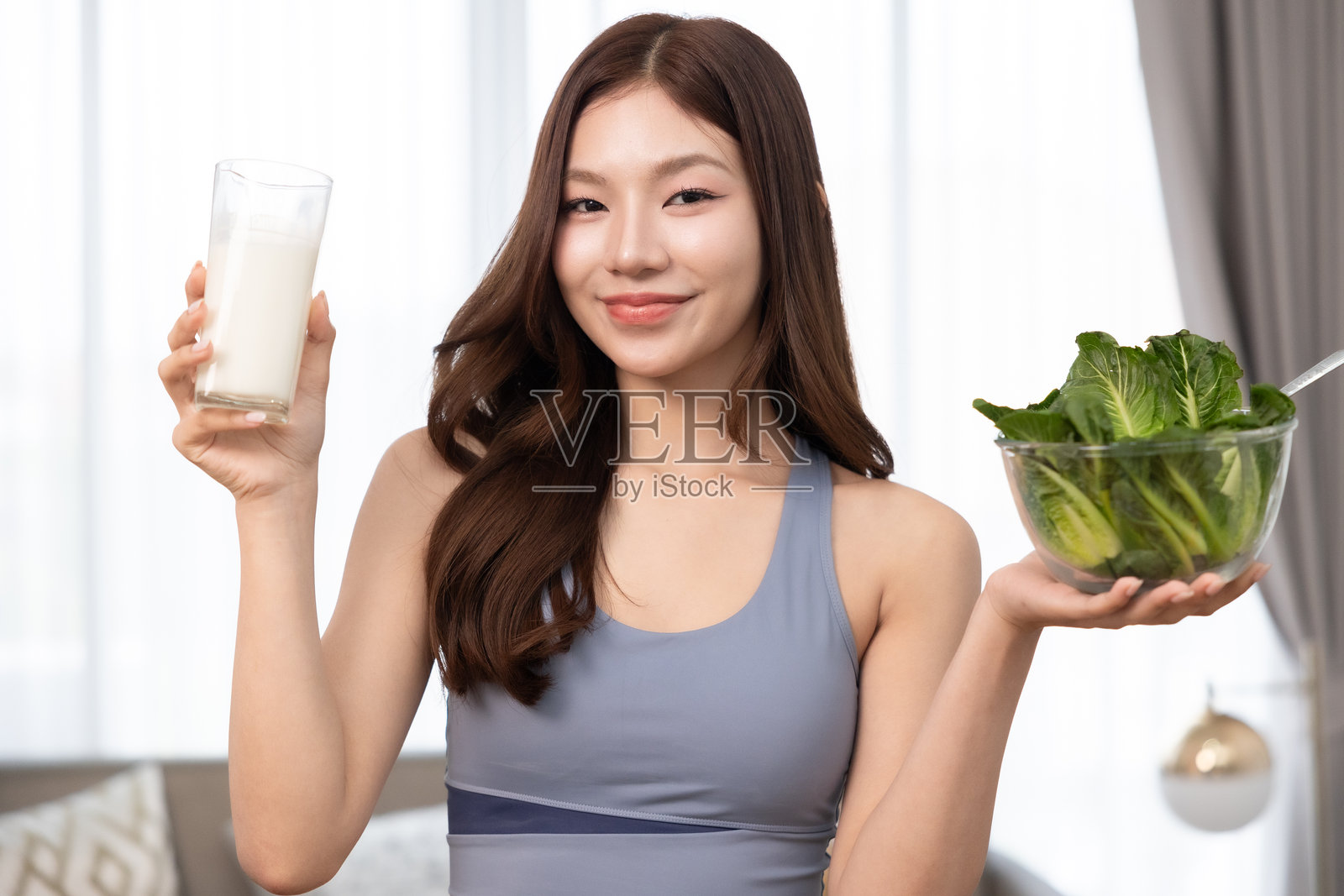 年轻的亚洲运动女性在家准备蛋白质奶昔。饮食与健康食品。训练后放松。美丽的年轻女性在锻炼后喝牛奶。健康生活方式的概念。照片摄影图片