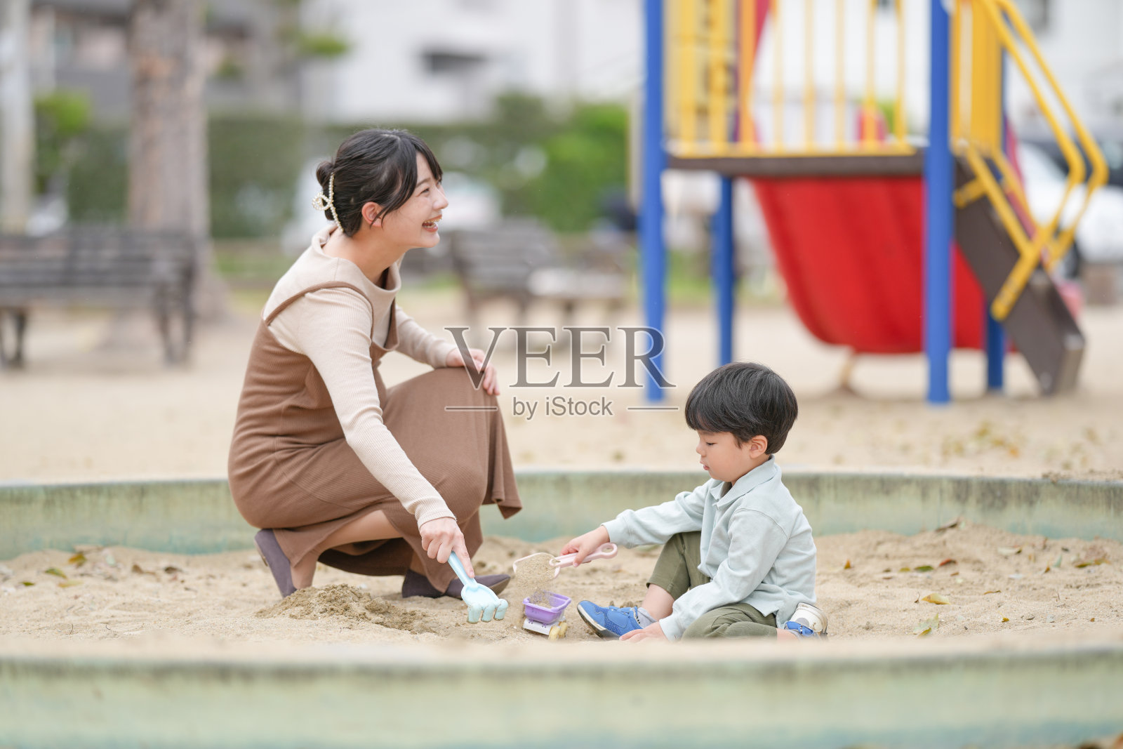 一位女性和一个孩子正在沙箱里玩耍照片摄影图片