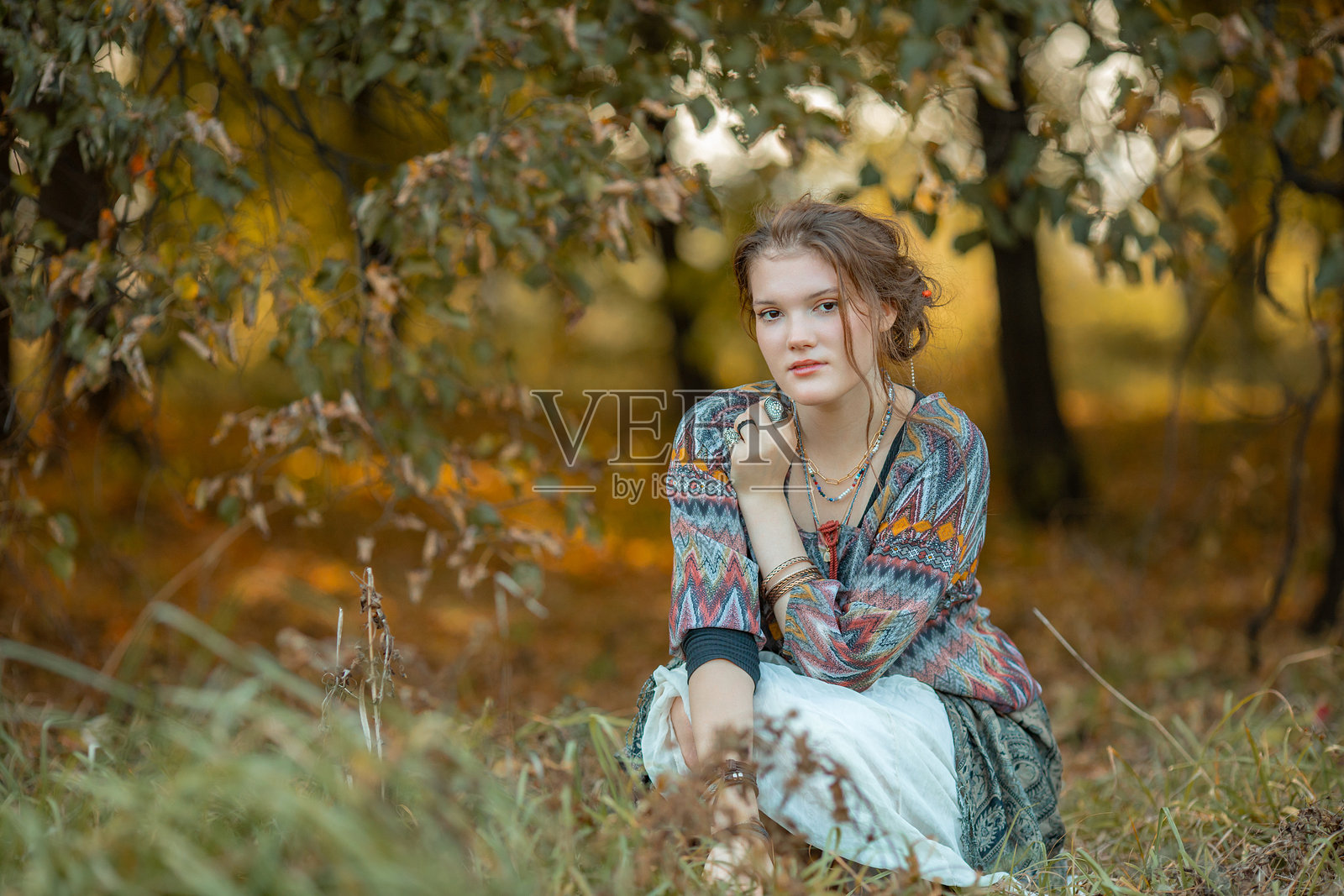 年轻女性穿着波西米亚风格的服装在秋季森林中摆姿势照片摄影图片