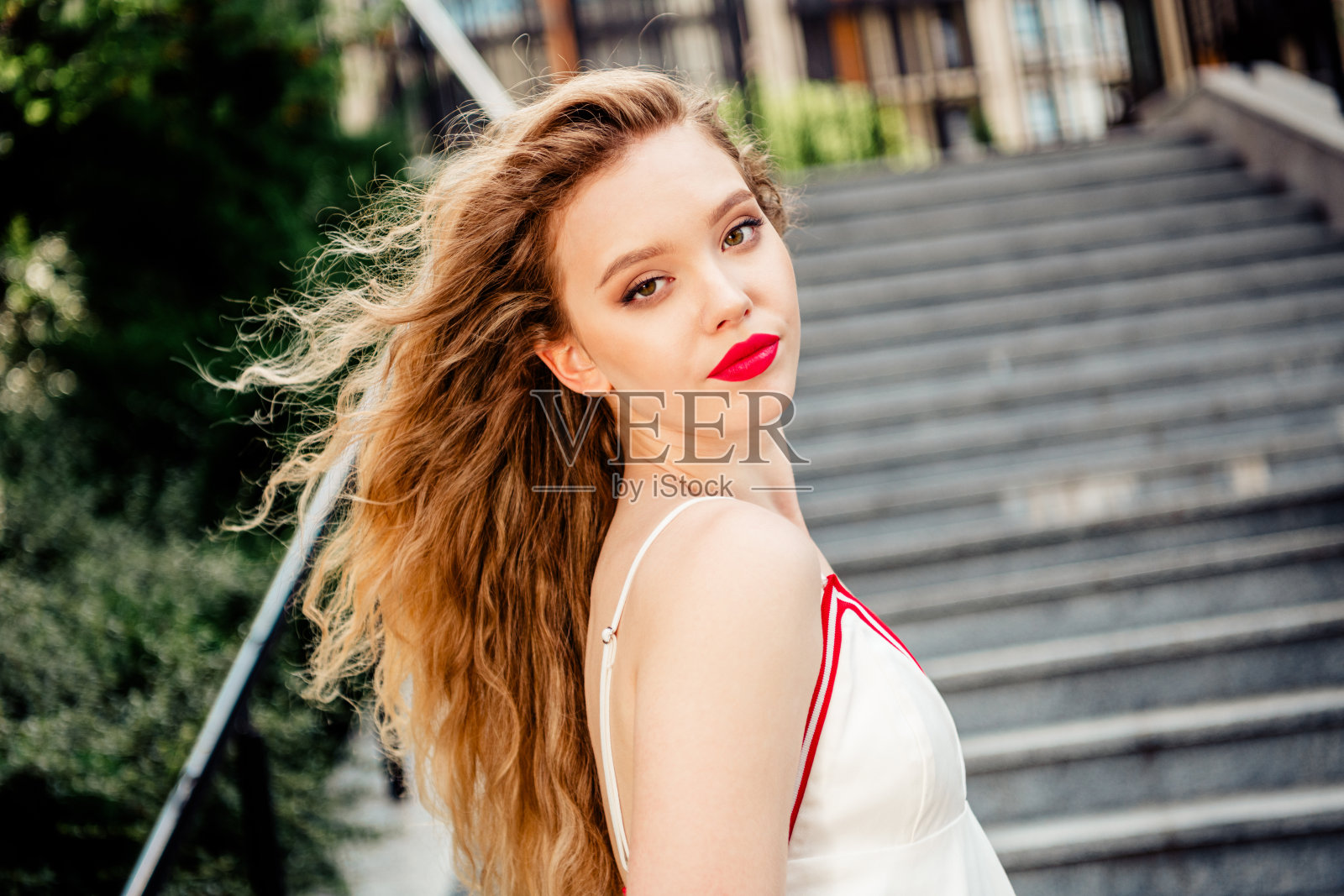 年轻女性在阳光明媚的户外,背景是城市楼梯,轻松摆姿势。照片摄影图片