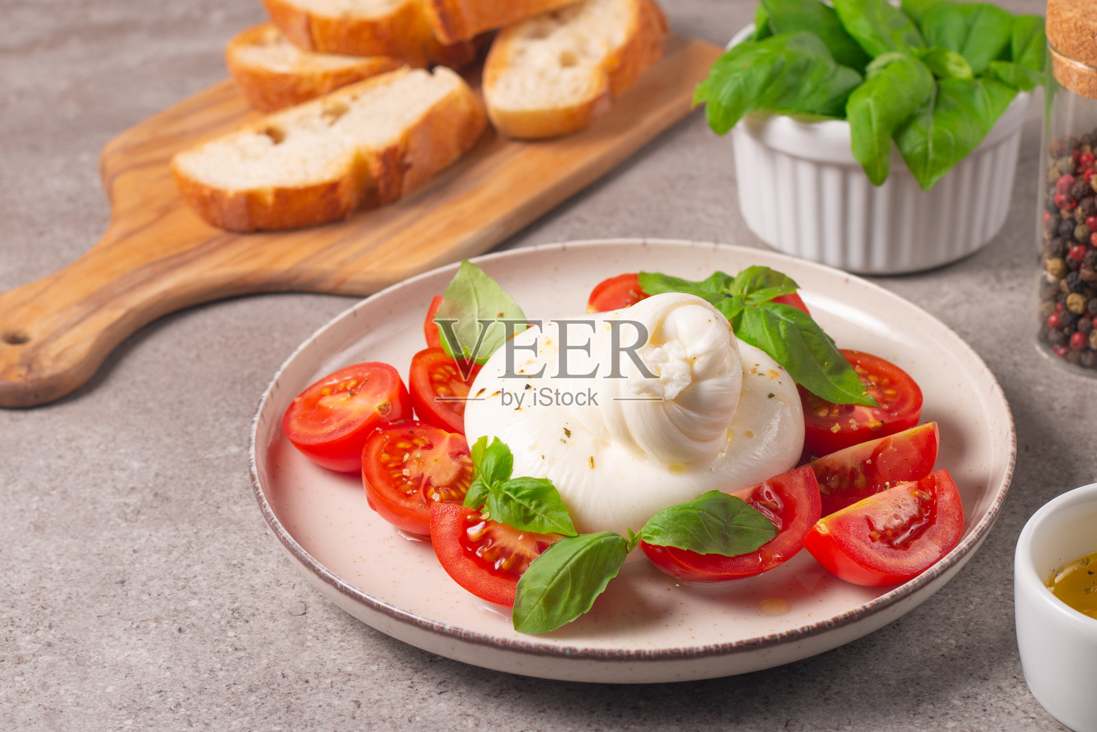 美味的意大利卡普雷塞沙拉,配有切片马苏里拉奶酪、西红柿、罗勒,背景是面包。照片摄影图片